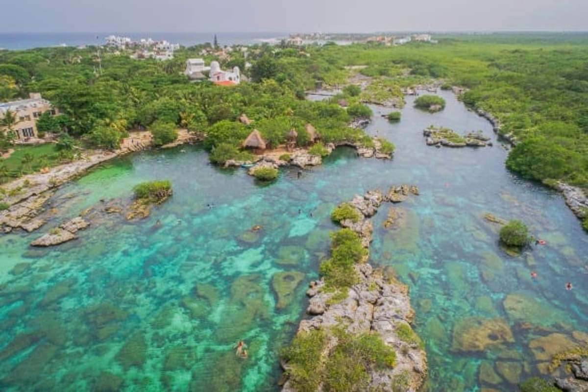 Aerial view of Yal-Ku Lagoon in Mexico, showcasing clear turquoise water, small islands, and lush greenery.