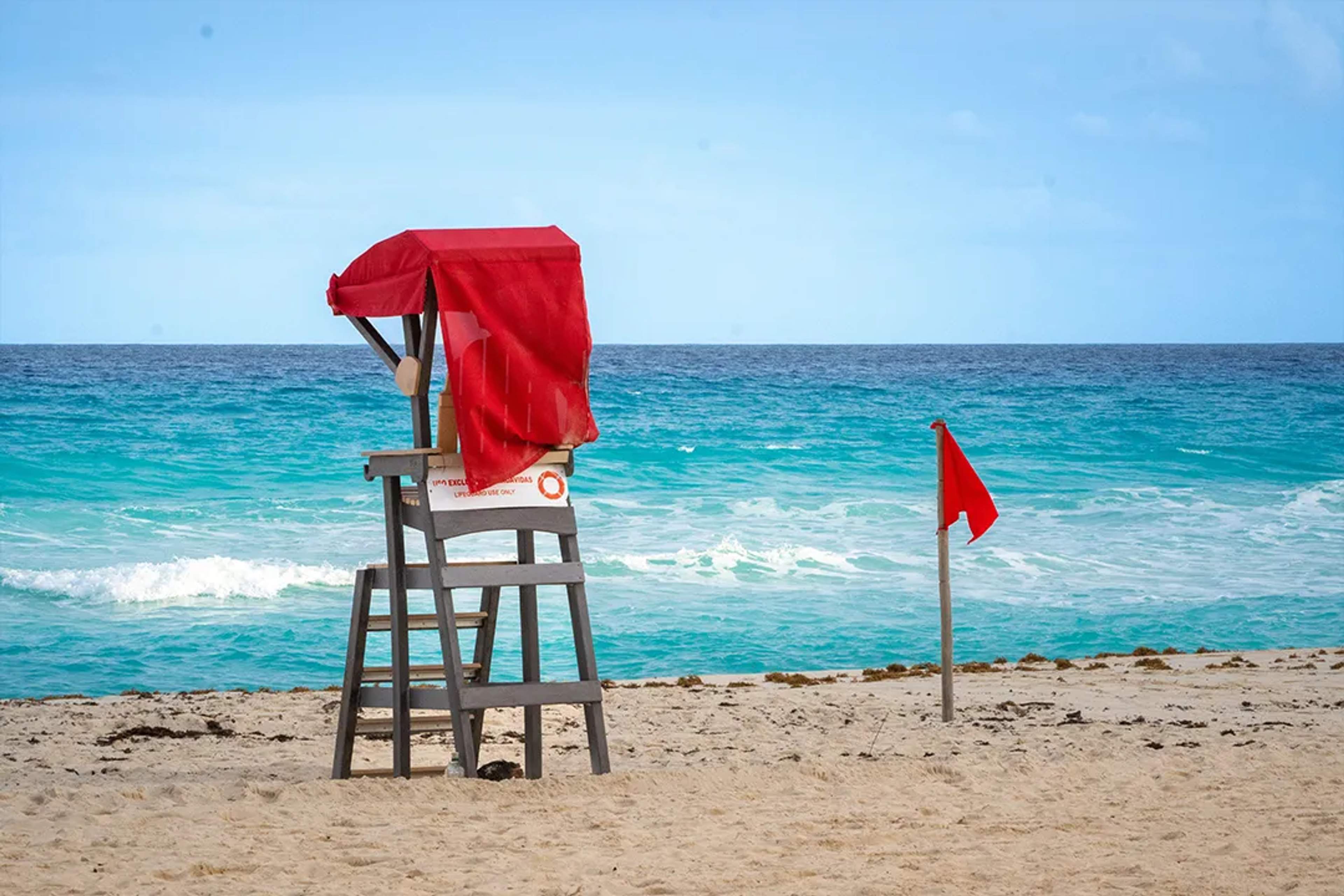 Red flag warning on Cancun beach with lifeguard tower, ocean safety conditions in Hotel Zone