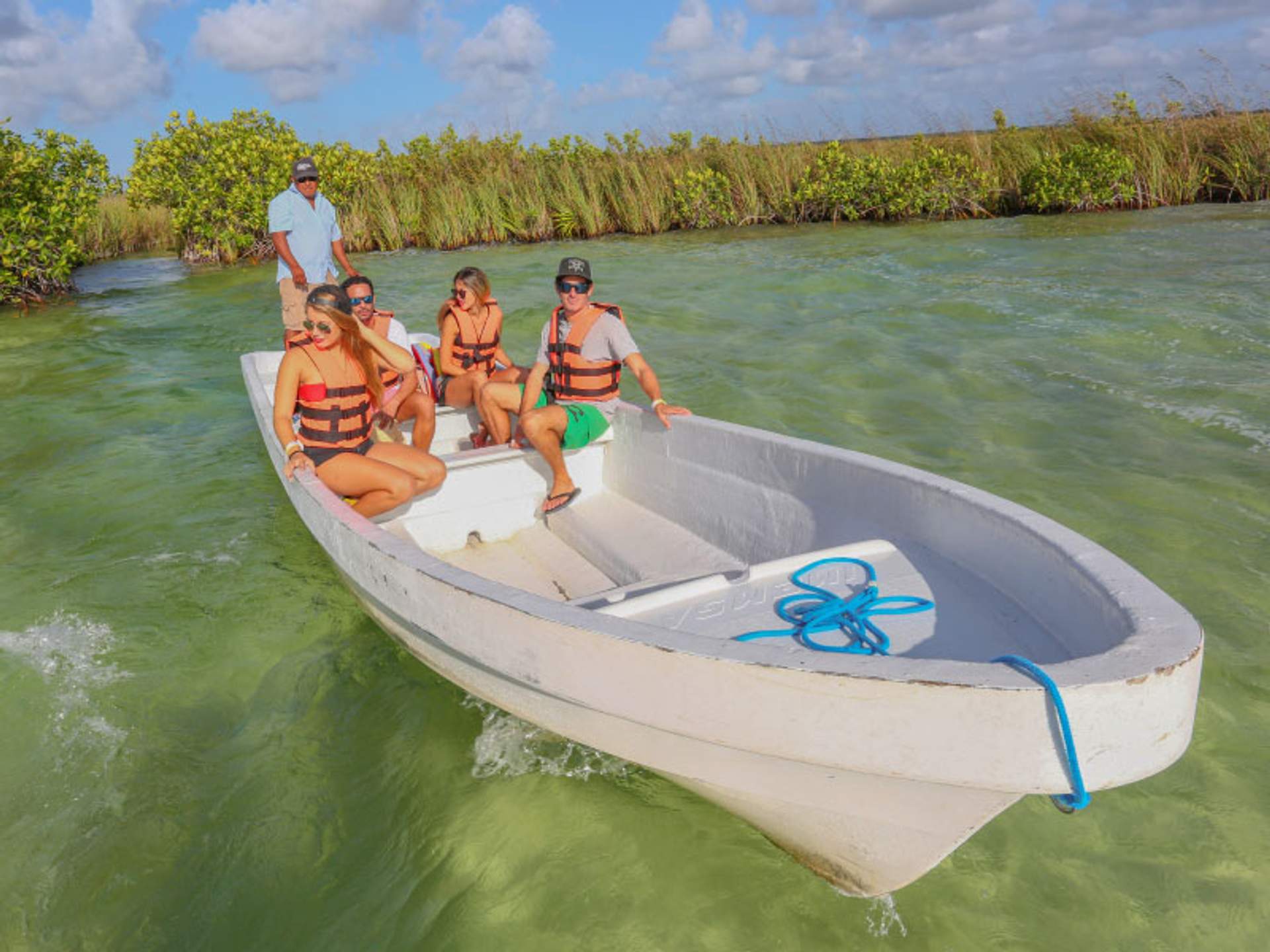 Group of five people enjoying a boat ride in Cancun's waters, surrounded by nature.