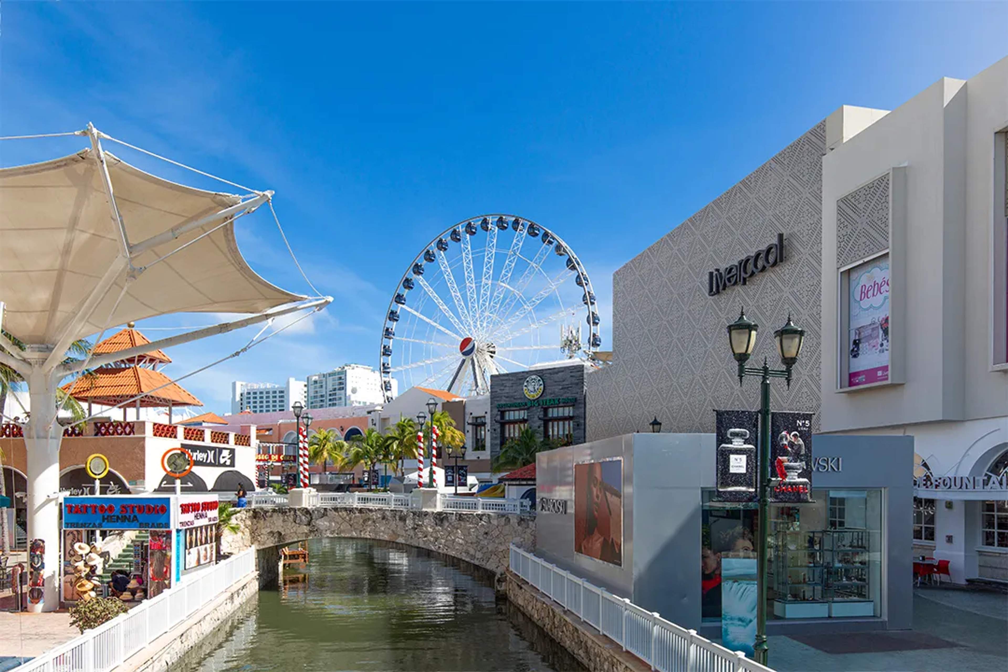 Plaza La Isla en Puerto Vallarta, con rueda de la fortuna y canal bajo un cielo despejado.