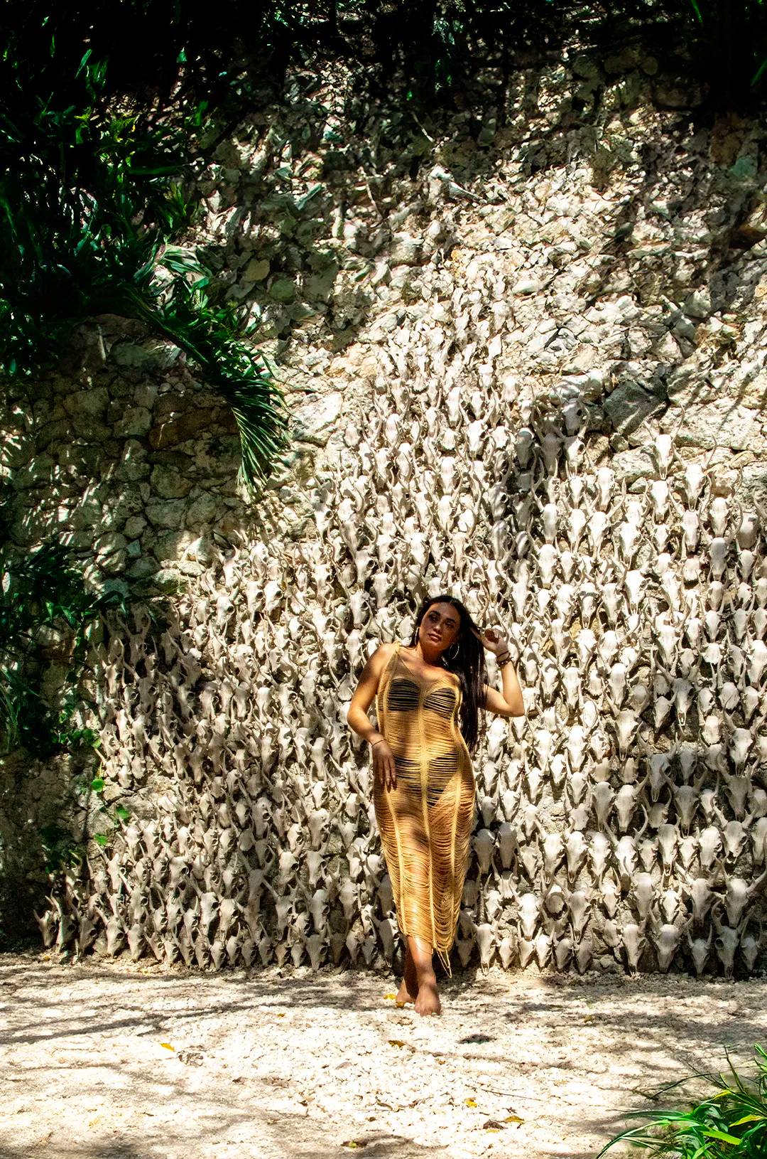 Woman posing in front of a skull wall in Tulum