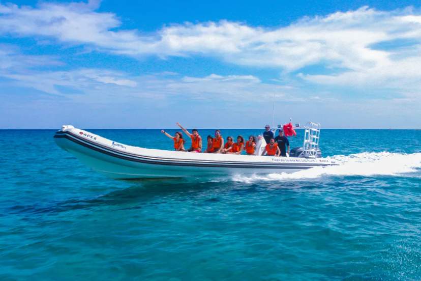 Pequeño grupo disfrutando de un tour en lancha rápida sobre aguas turquesas bajo un cielo brillante.