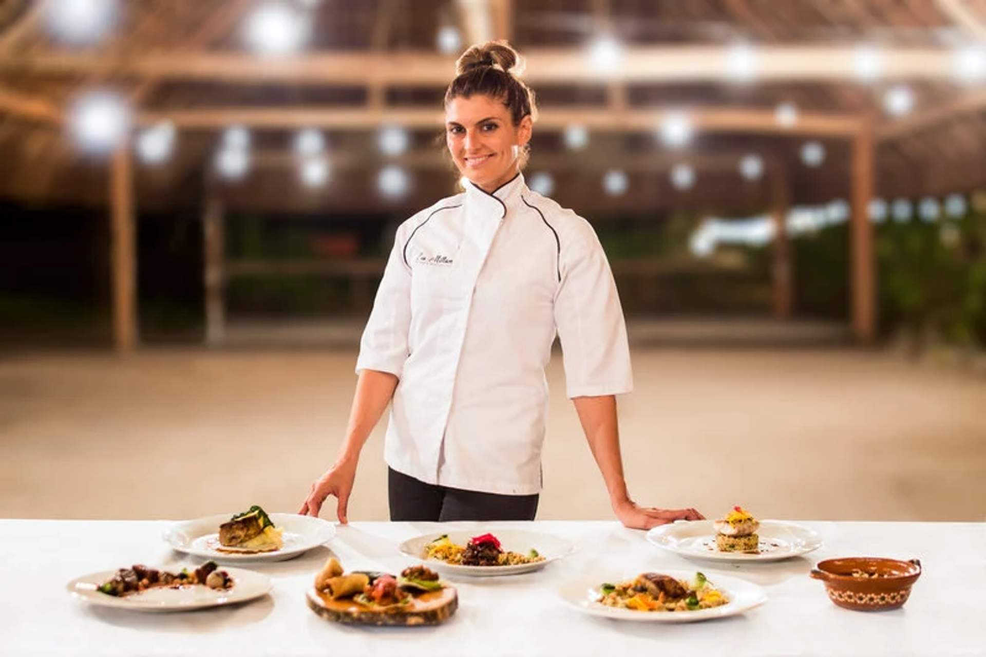 La chef Eva Millan presenta una exquisita selección de platos, mostrando sus habilidades culinarias en una boda en Punta Venado, Cancún.