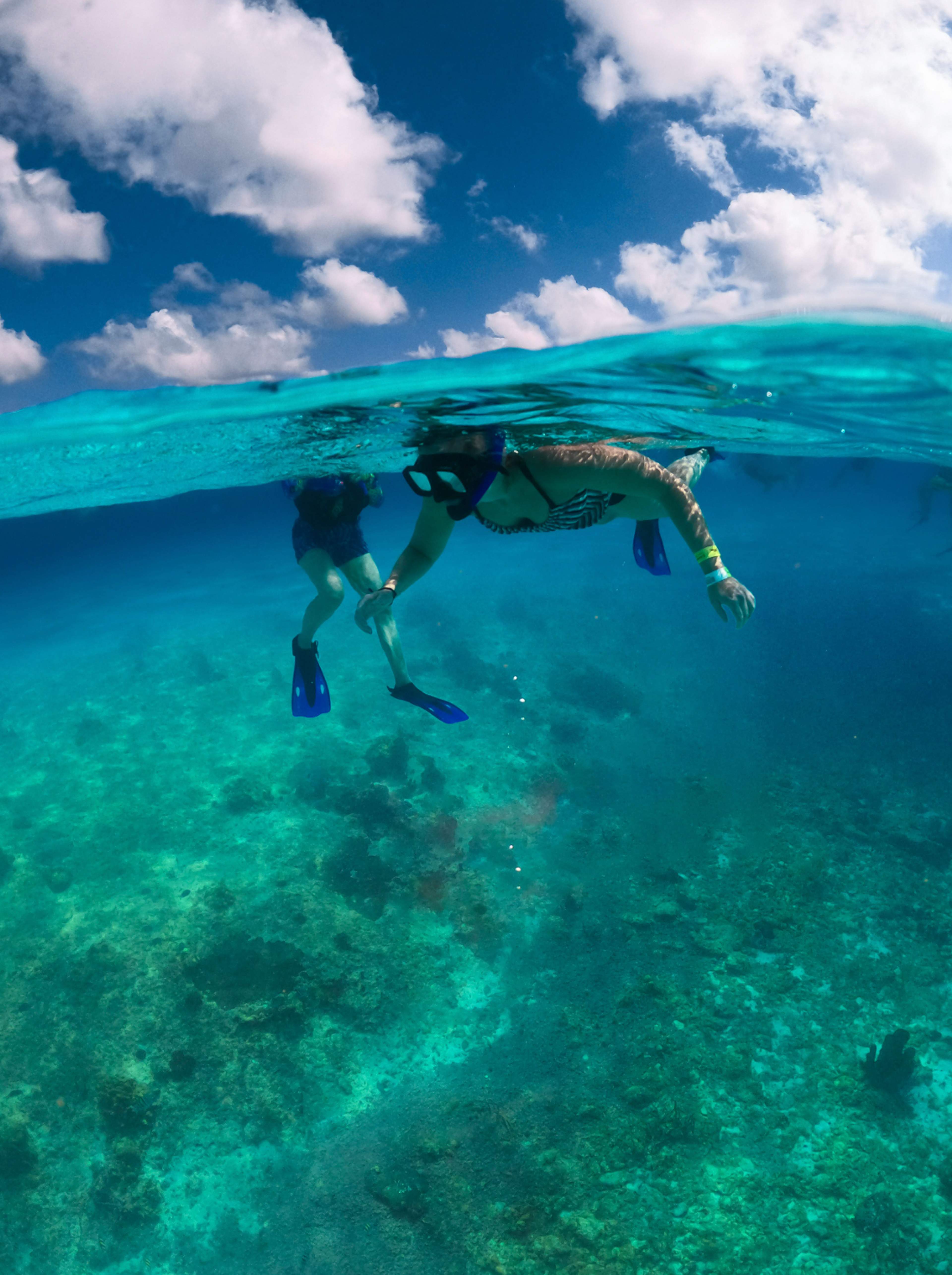 Dos personas haciendo esnórquel en las aguas turquesas de Cancún, observando la vibrante vida marina.