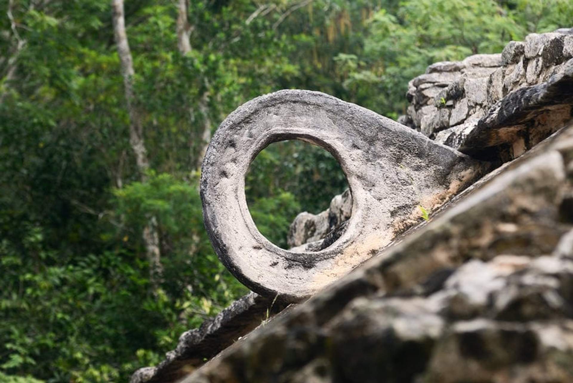 Stone ring from the ancient Mayan ball game court in Cobá, surrounded by lush jungle.