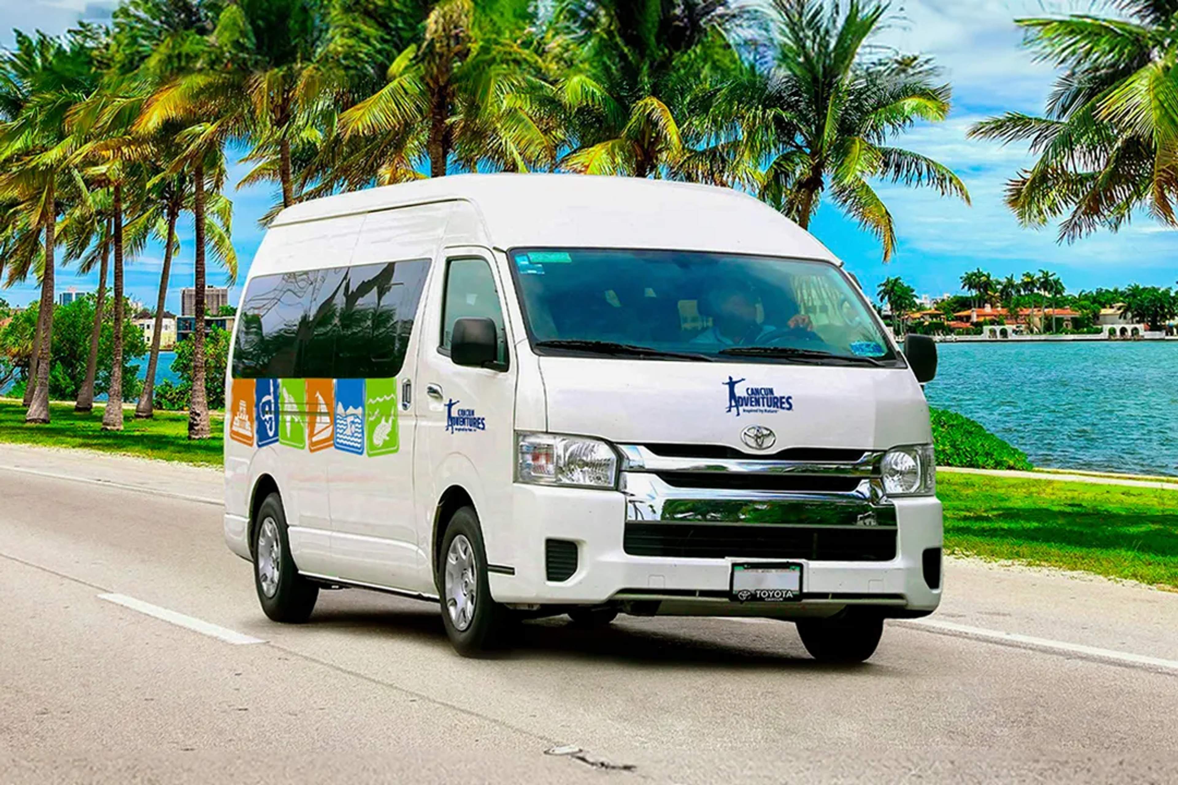 Cancun Adventures van driving along a palm-lined road by the water on a sunny tropical day.
