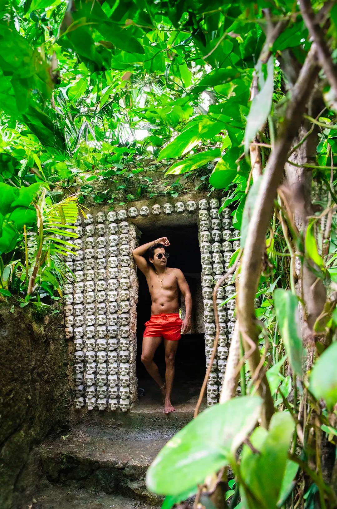Man posing at an entrance decorated with skulls in Tulum, a photogenic and unique spot.