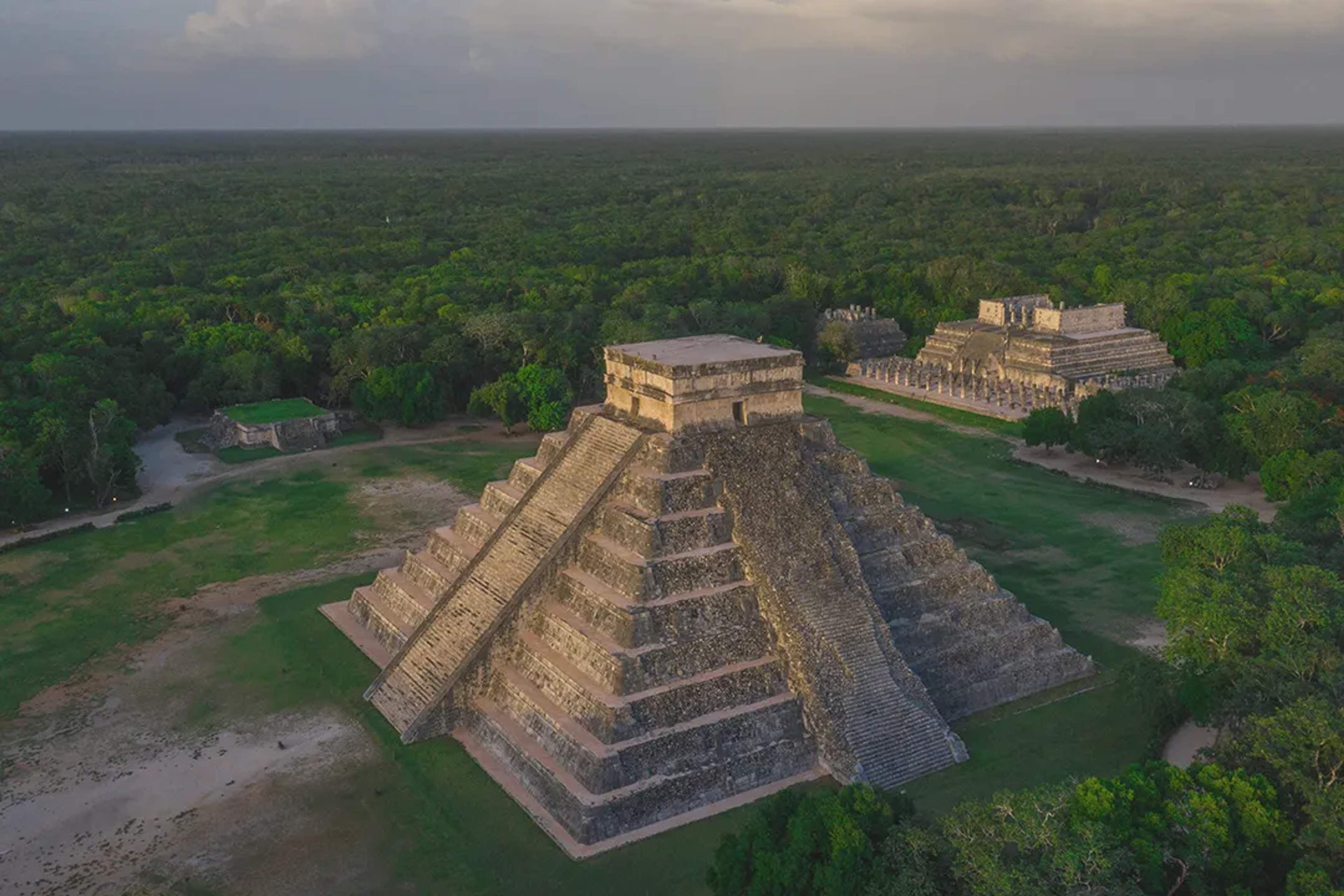Majestic view of Chichén Itzá’s pyramid surrounded by jungle and ancient Mayan ruins.
