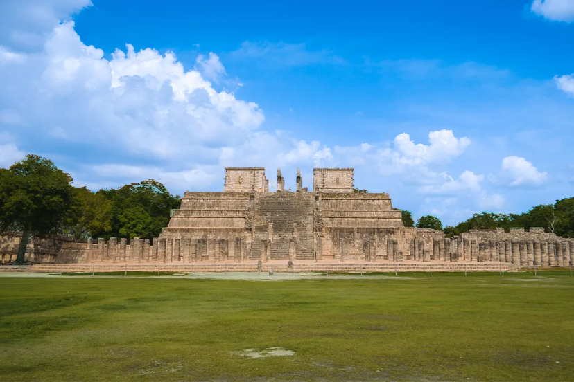 The Temple of the Warriors in Chichen Itza, showcasing its grand staircase and columns under a blue sky.