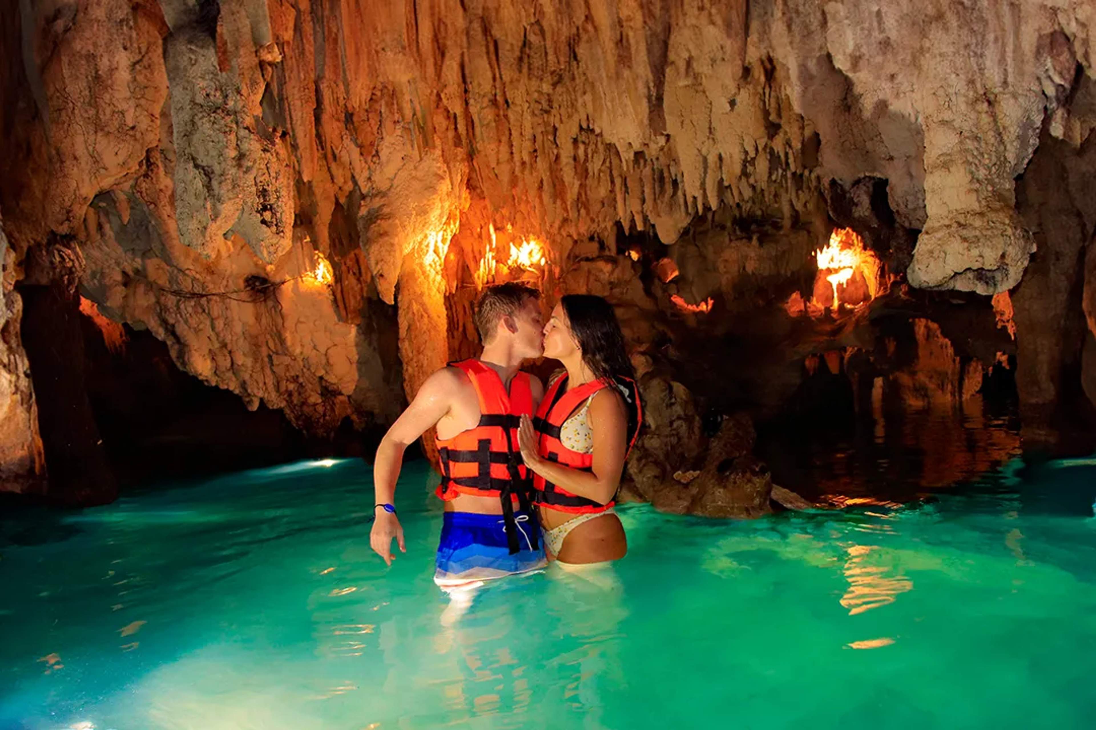 Couple swimming in a crystal-clear cenote in Cancún, enjoying a romantic cave experience with turquoise waters