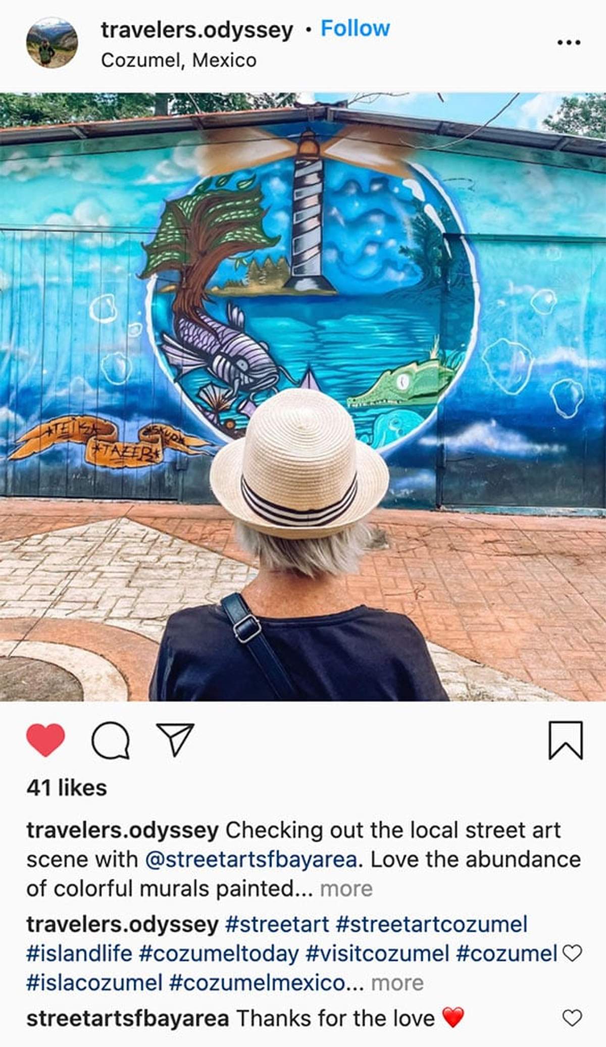 A person wearing a hat admiring a colorful mural featuring a lighthouse and marine life in Cozumel.