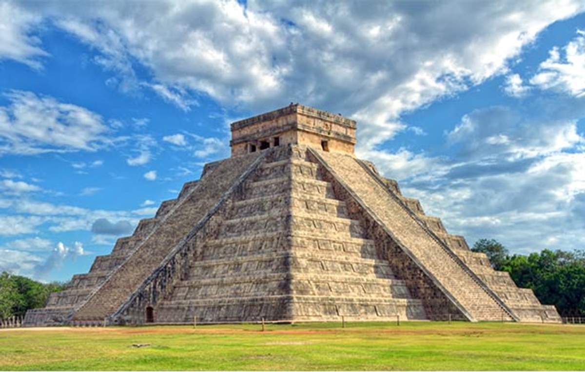 The Temple of Kukulkan at Chichen Itza, a massive step pyramid under a partly cloudy sky.
