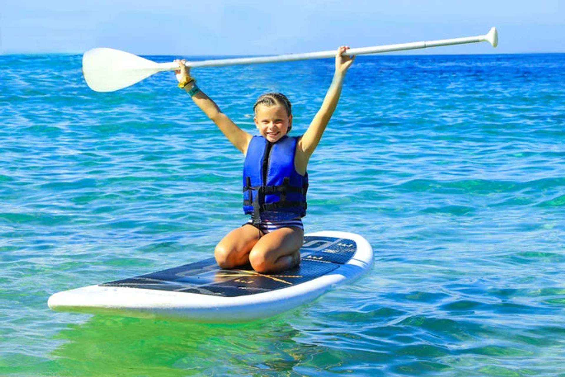 Child enjoying paddleboarding, perfect for kid-friendly water activities in Cancun.