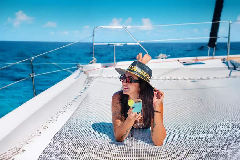 Young woman drinking a cocktail on a Cancun catamaran.