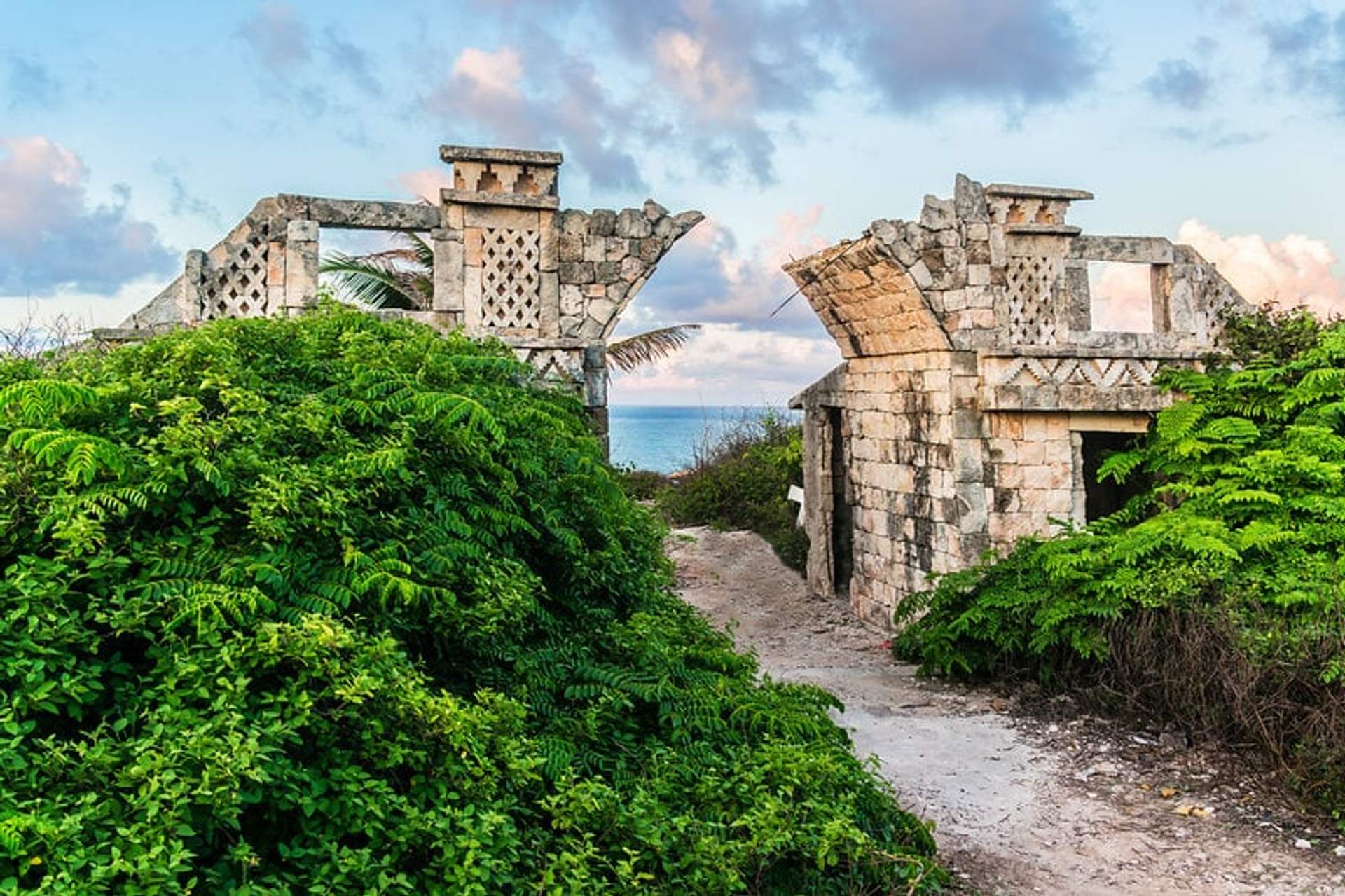 Ruins of the Ixchel temple on Isla Mujeres, showcasing ancient stone architecture amidst lush greenery with a view of the Caribbean Sea.