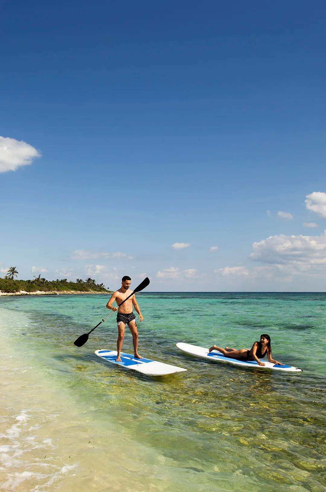 Pareja disfrutando con paddle boards en una playa tranquila en Cancún.
