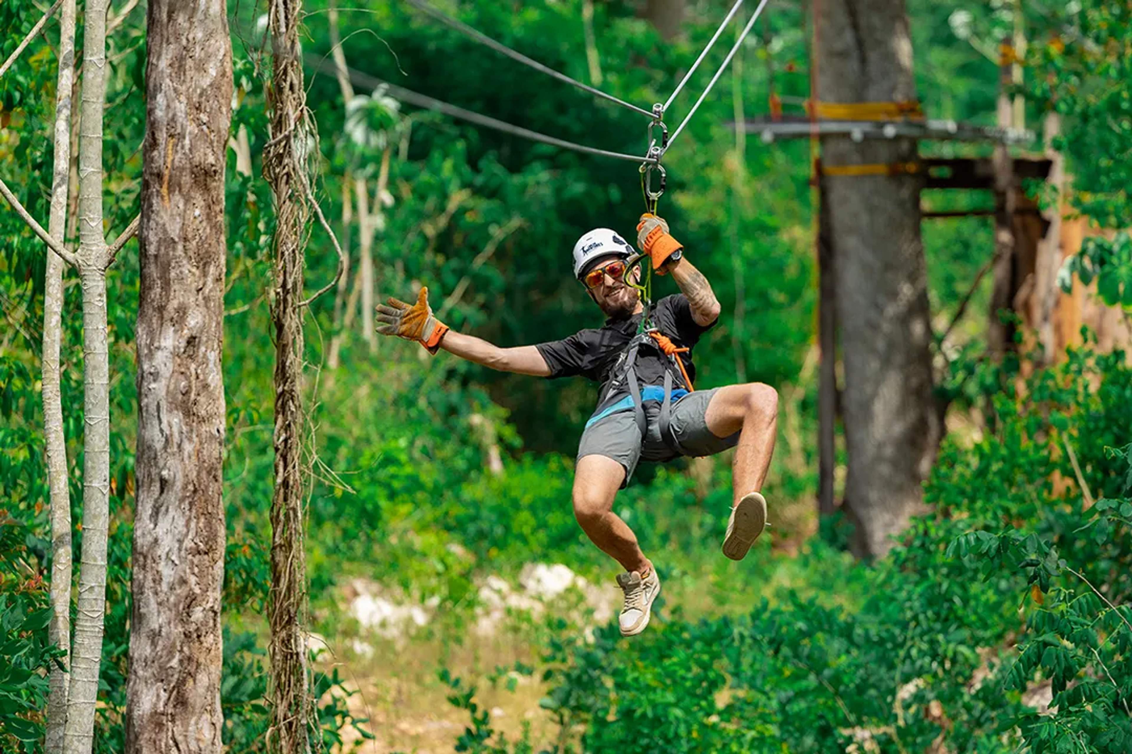 Man ziplining through the jungle with safety gear, enjoying an exciting outdoor adventure in Cancun