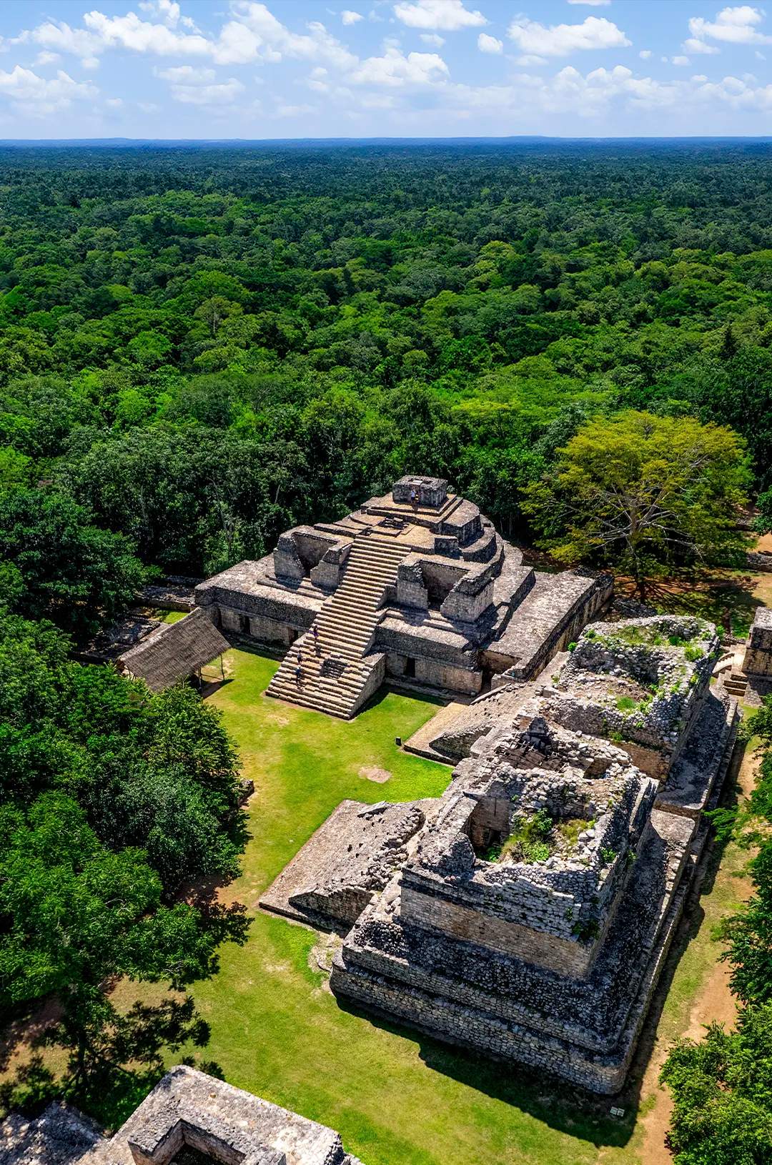 Vista aérea de las ruinas de Ek Balam, rodeadas de exuberante vegetación y antiguas estructuras.