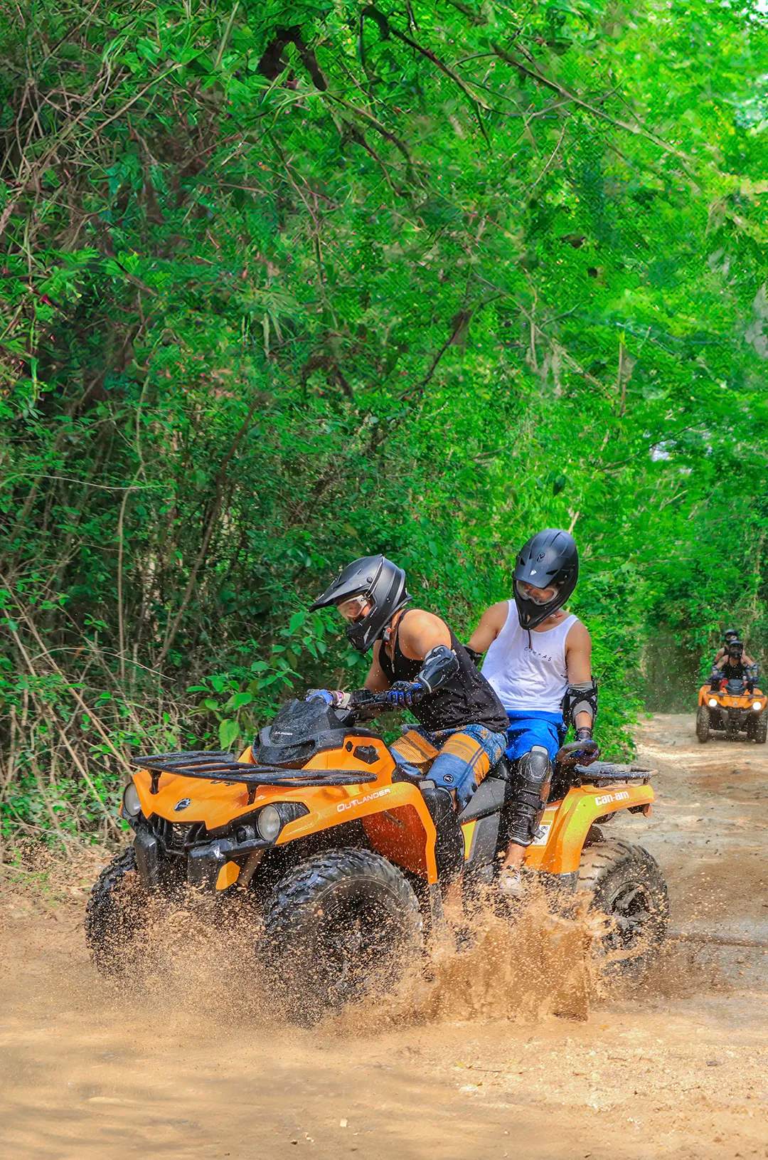 People on ATVs riding through a muddy path in an outdoor adventure in Cancun.