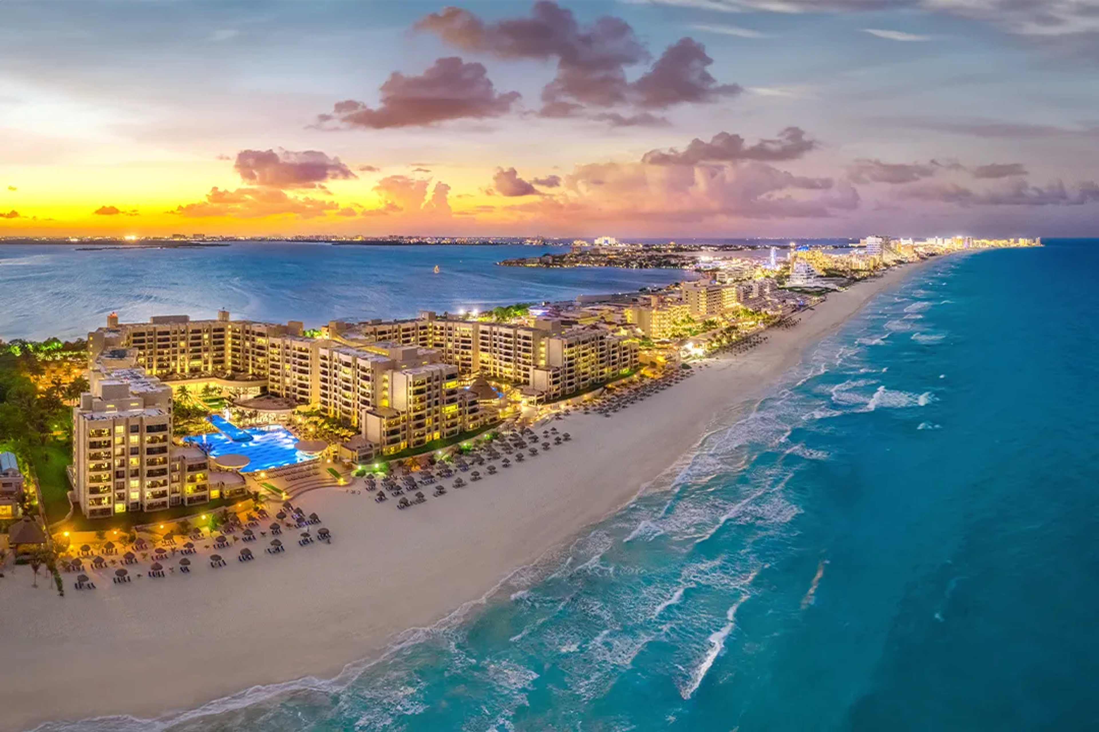 Vista nocturna de Cancún: diversión en la playa, piscinas iluminadas y vida nocturna vibrante.