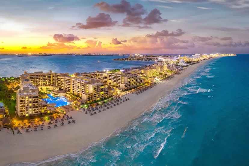 Vista nocturna de Cancún: diversión en la playa, piscinas iluminadas y vida nocturna vibrante.