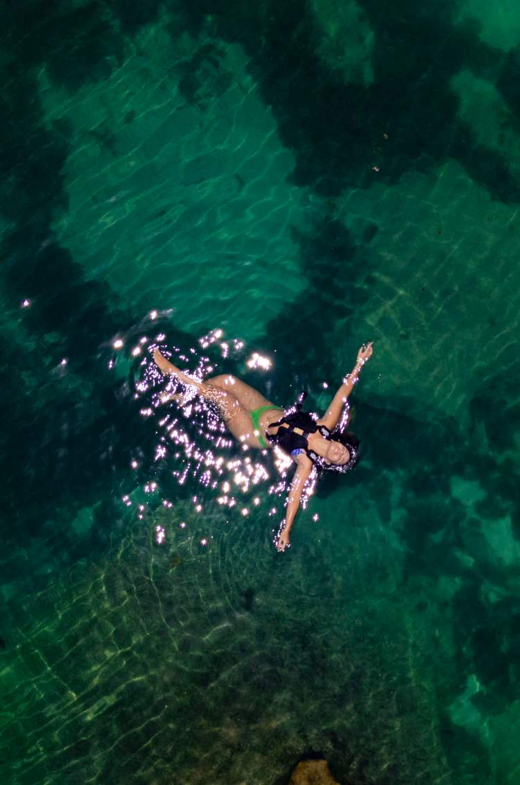 Mujer flotando tranquilamente en agua turquesa clara