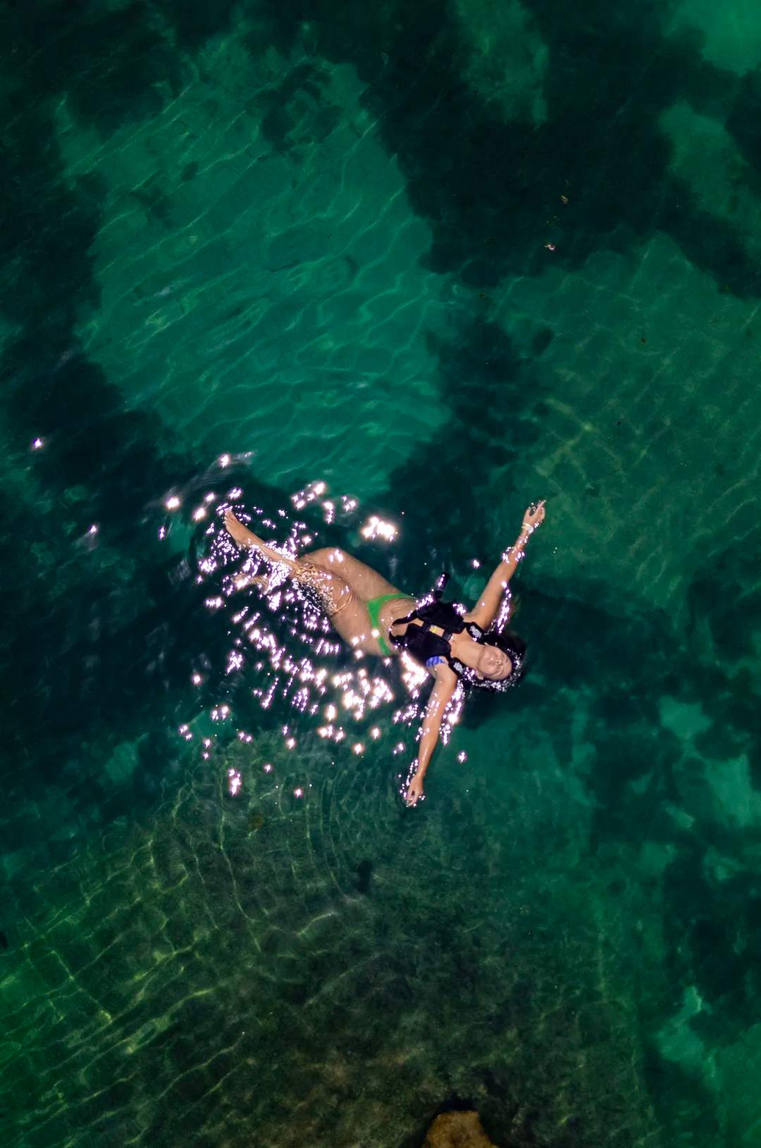 Woman floating peacefully in clear turquoise water