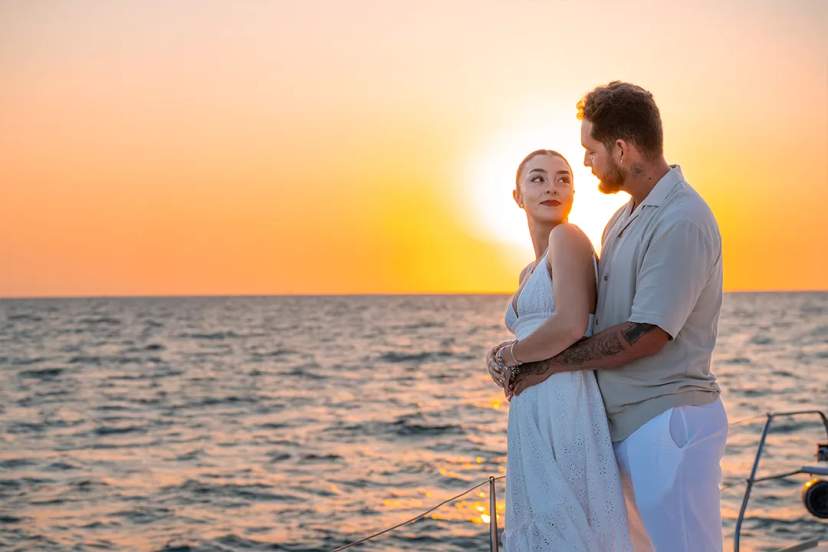Romantic couple embracing at sunset during a Sunset Sailing experience in Cancun with golden ocean views