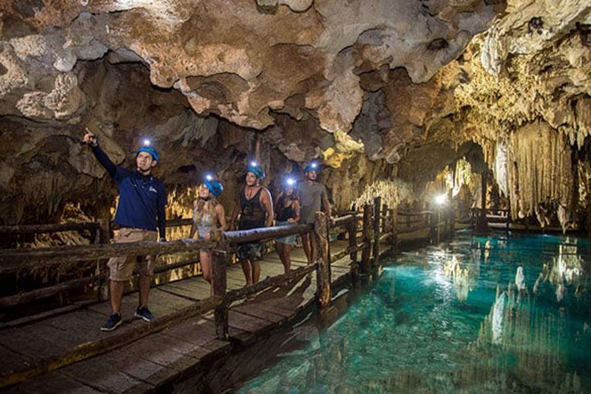 Pequeño grupo explorando una cueva iluminada con un guía en Cancún.