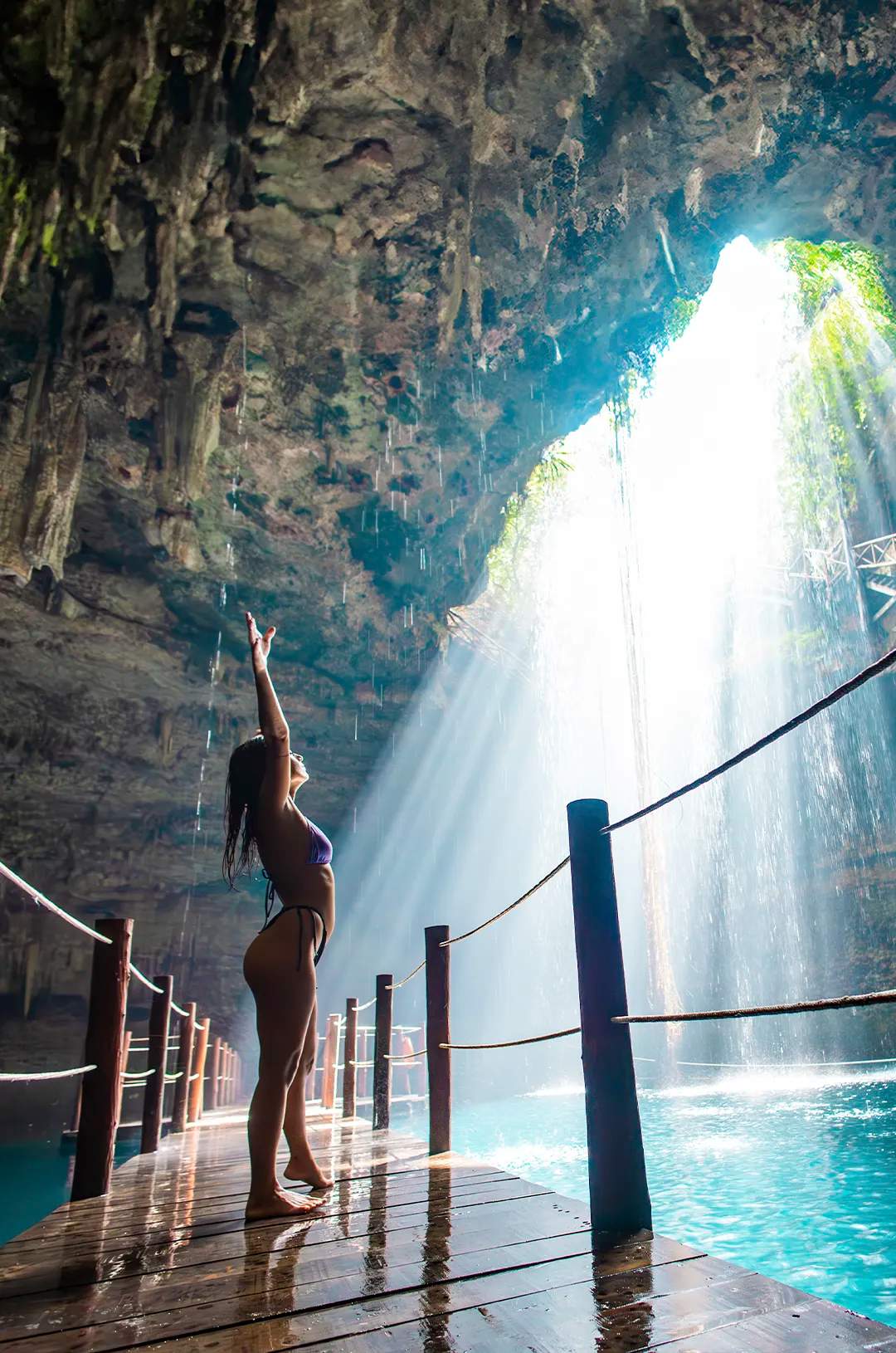 Persona disfrutando de un cenote en Yucatán, con luz natural entrando desde la caverna.