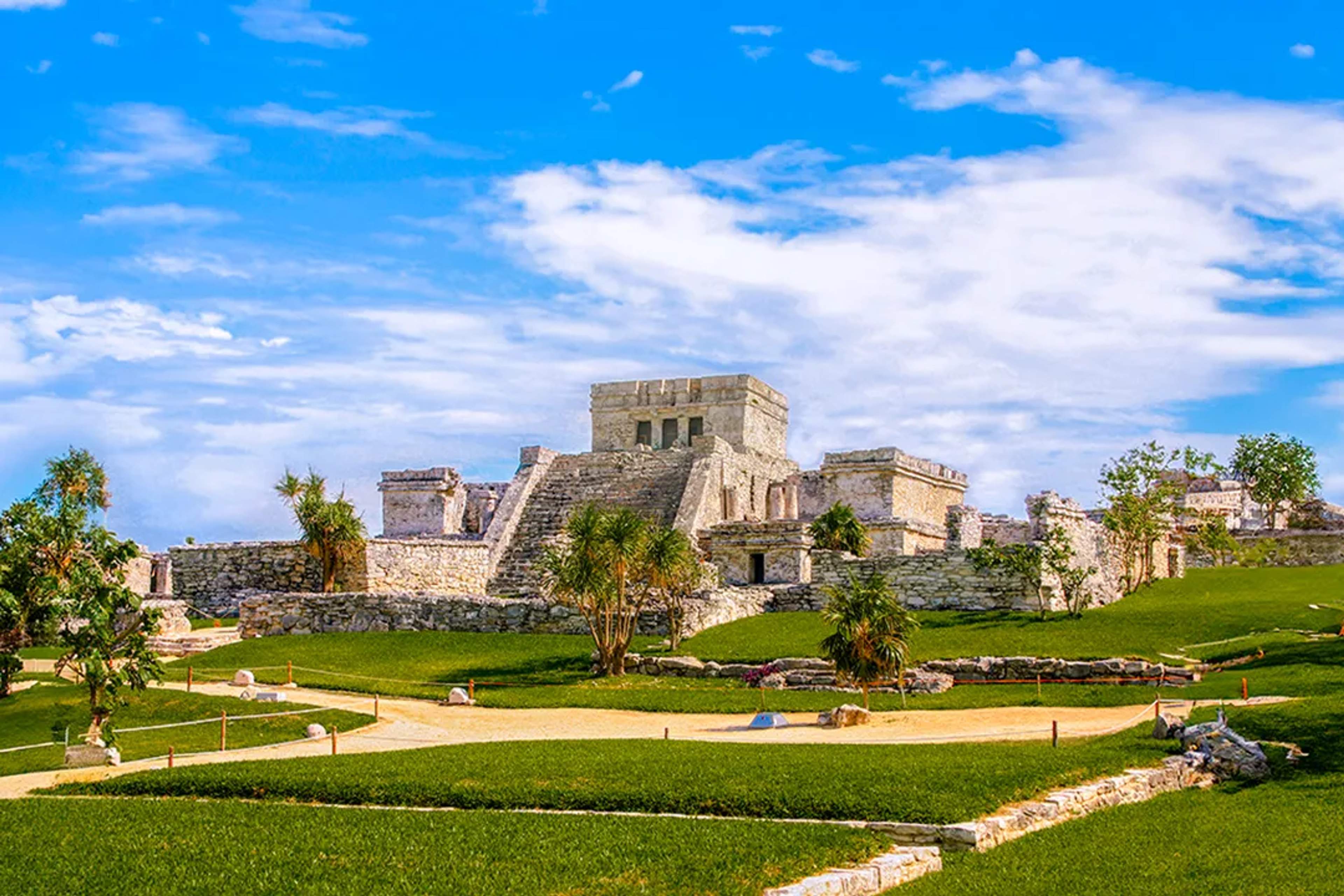 Ancient Mayan ruins of Tulum under a bright blue sky.