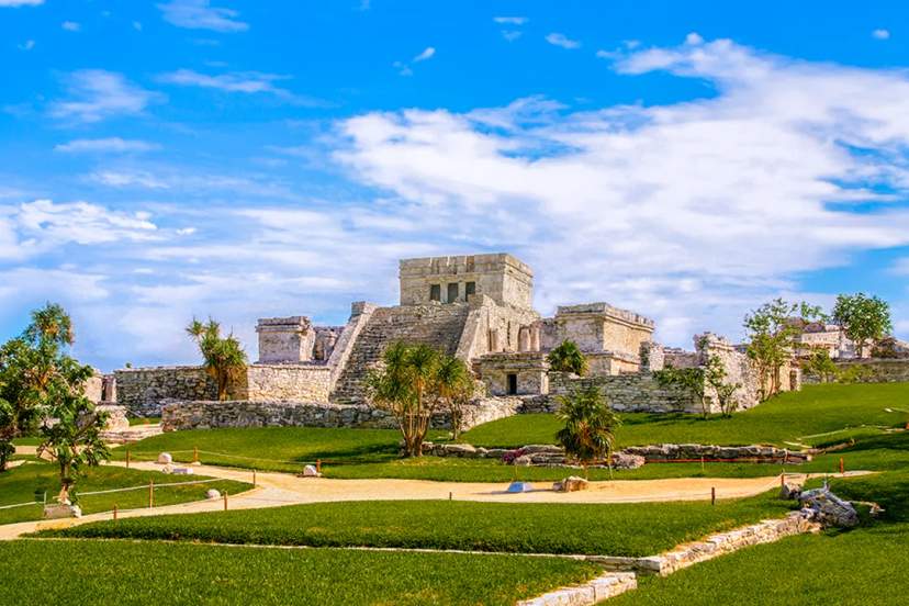 Ancient Mayan ruins of Tulum under a bright blue sky.
