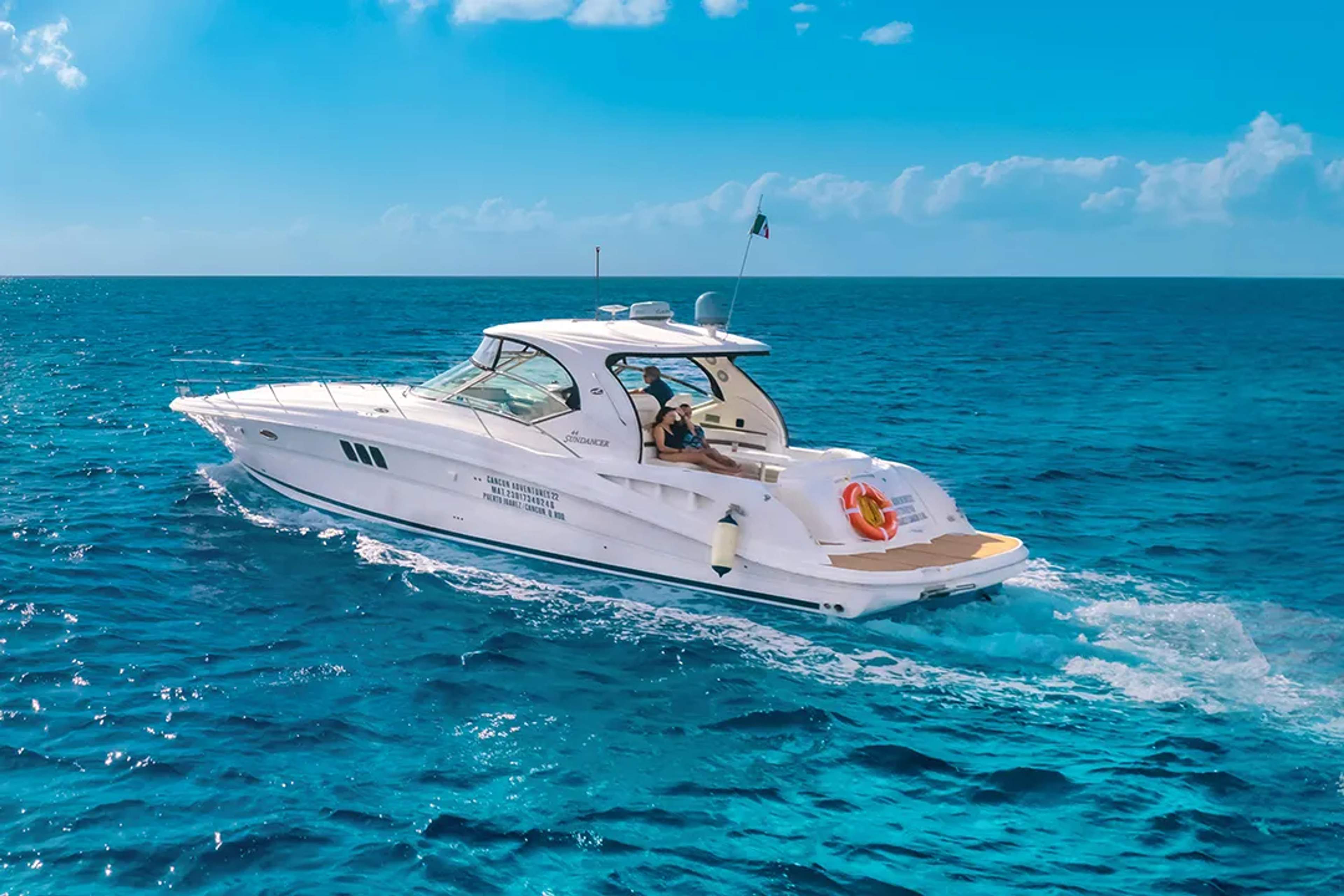 A luxury yacht cruising through the clear blue waters of Cancún under a sunny sky.