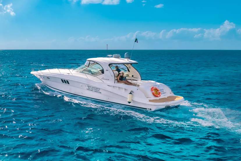 Un yate de lujo navegando por las aguas cristalinas de Cancún bajo un cielo soleado.