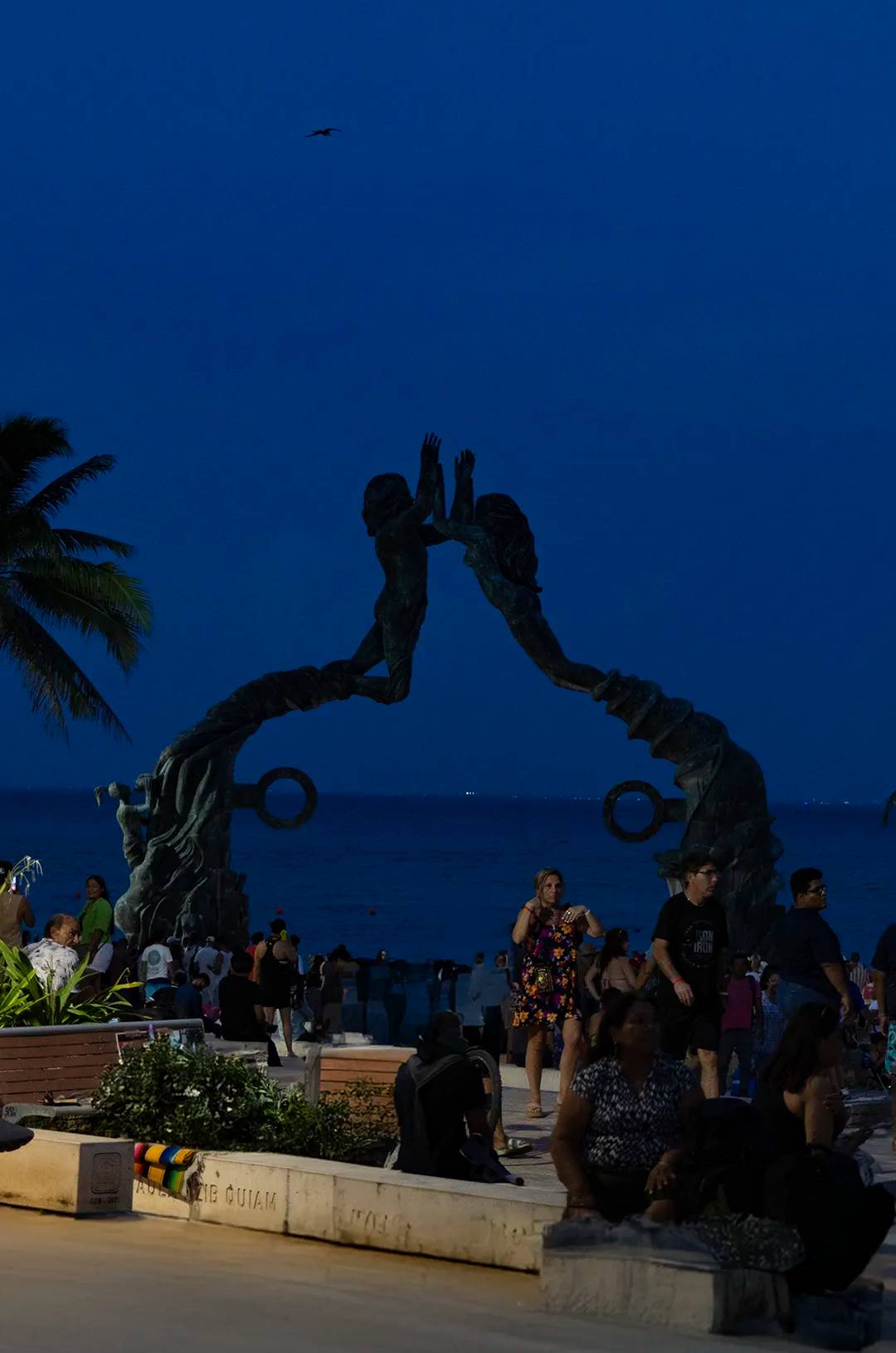 Explore Playa del Carmen at night and admire the famous Portal Maya sculpture.