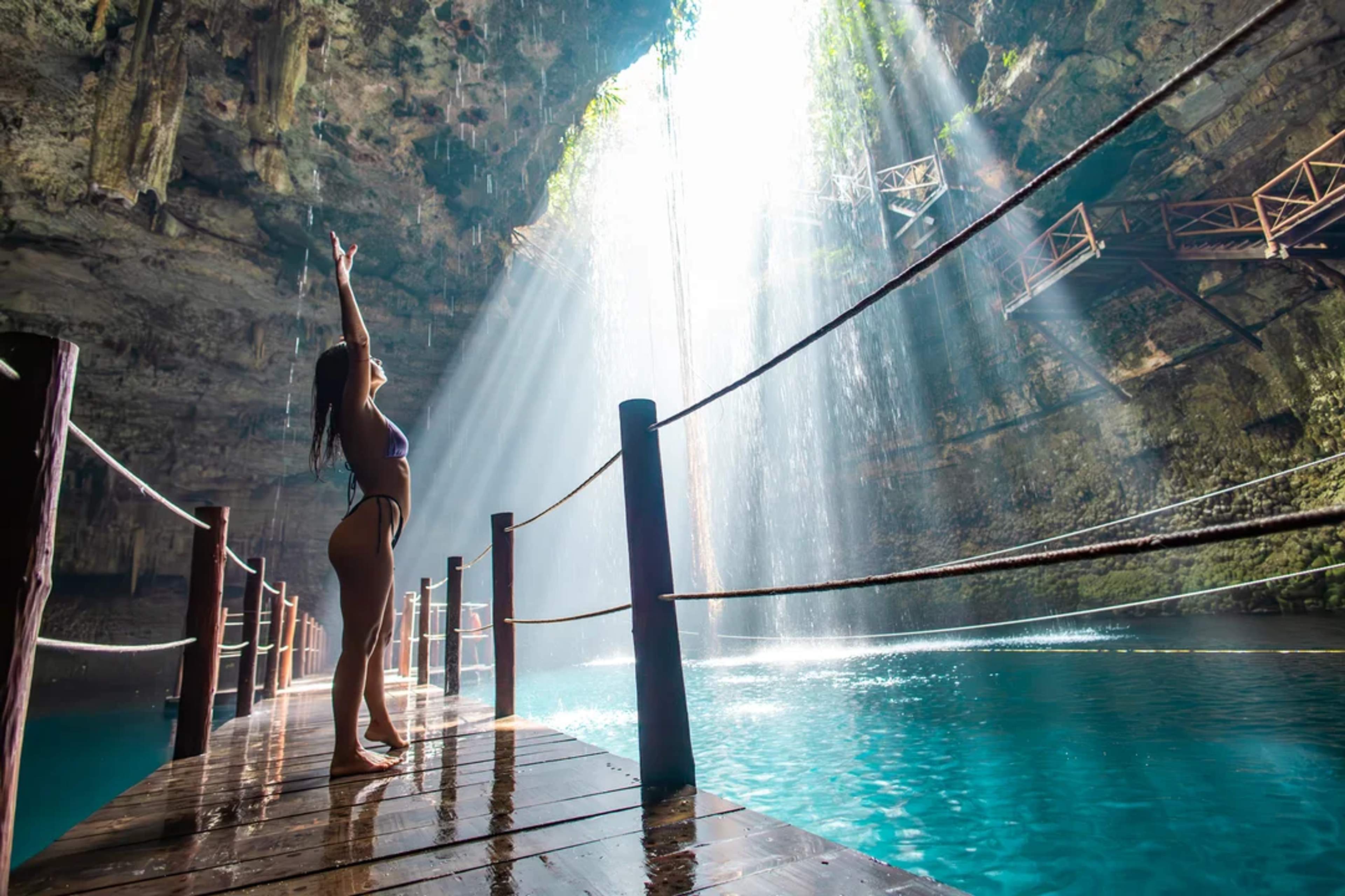 Feel the magic of Cenote Yalcobá as sunlight beams through the cave onto turquoise waters.