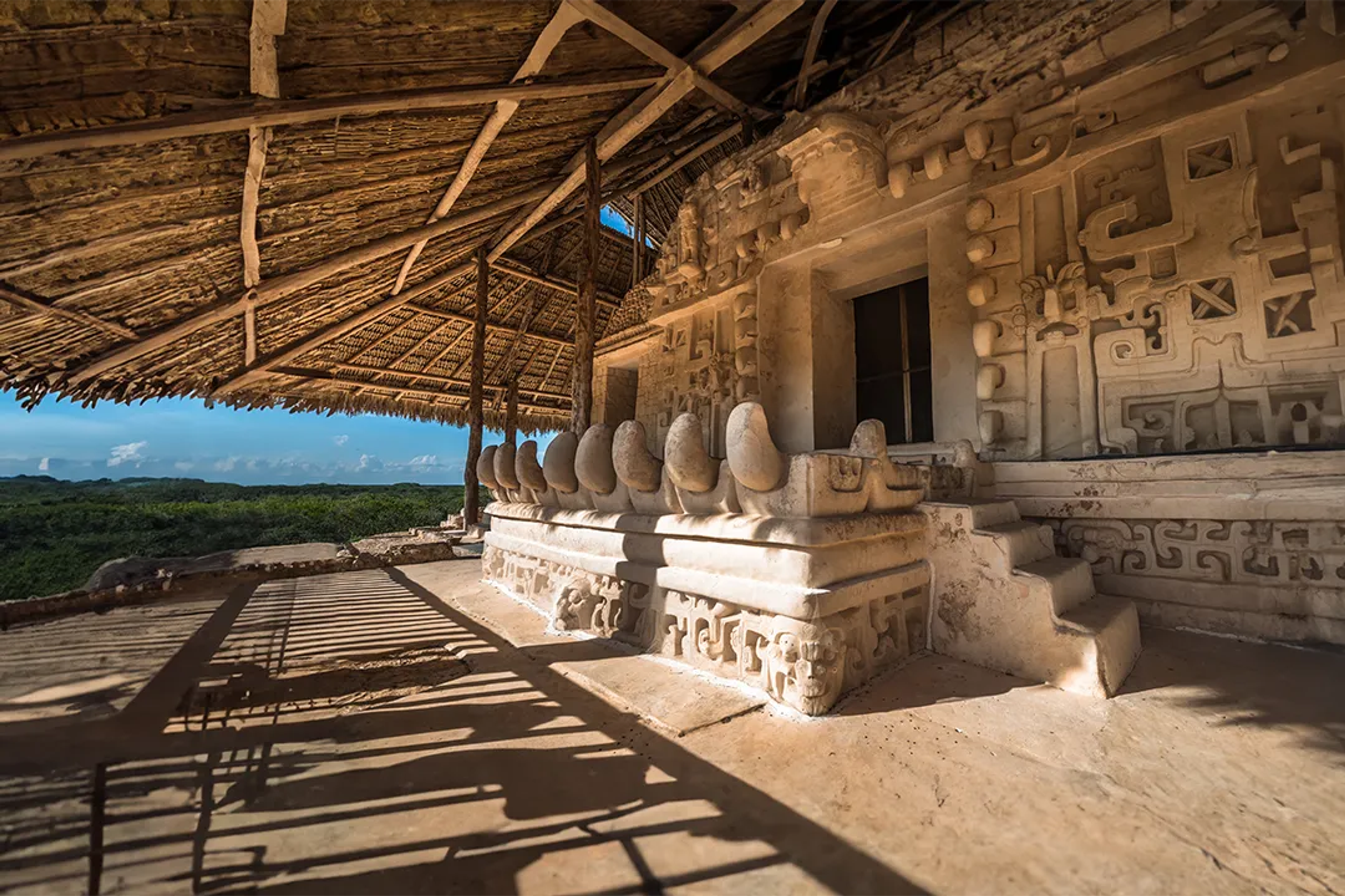 Ancient Mayan structure at Ek Balam, featuring intricate carvings and a thatched roof.