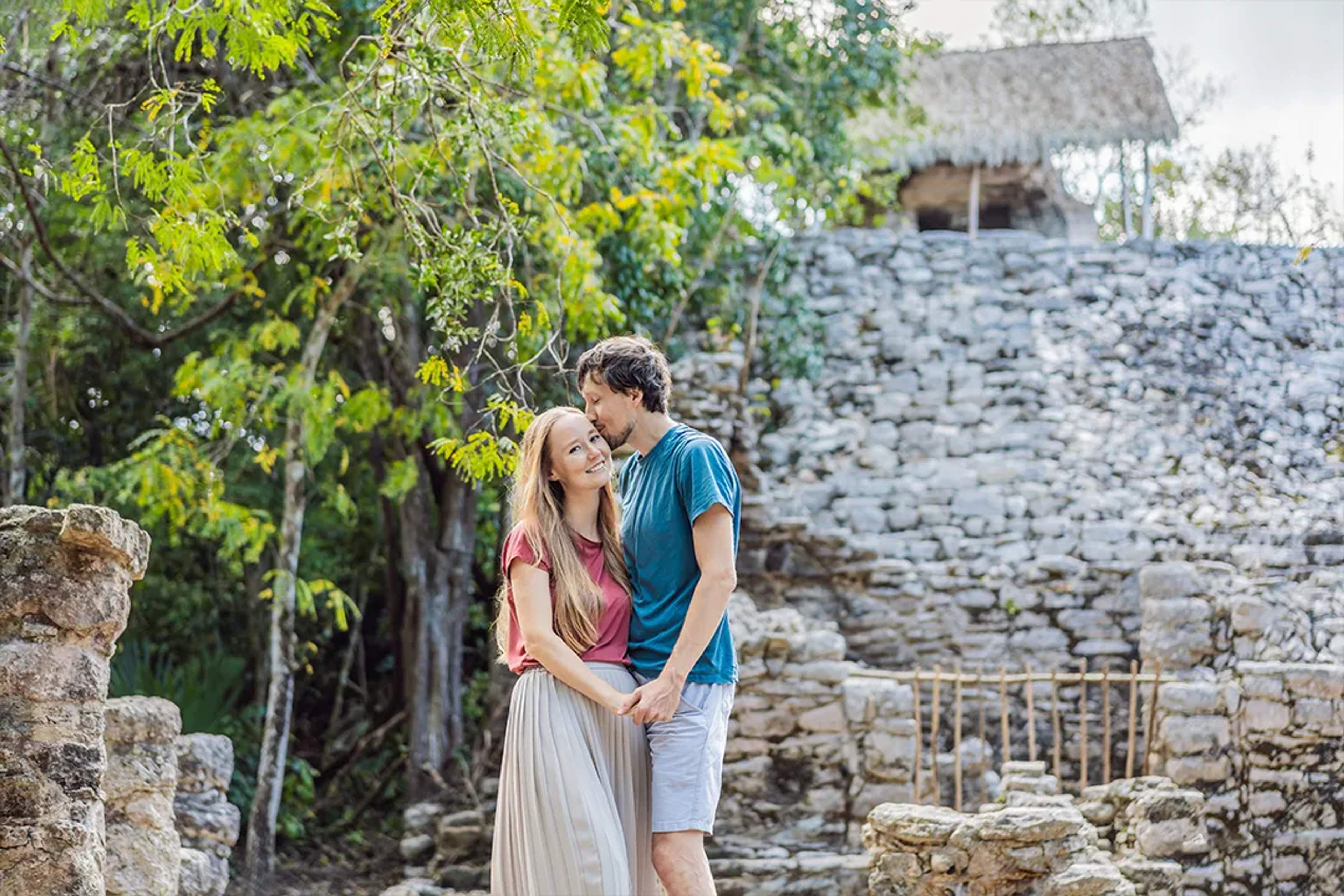 Couple holding hands at ancient Mayan ruins surrounded by jungle during romantic cultural tour in Riviera Maya
