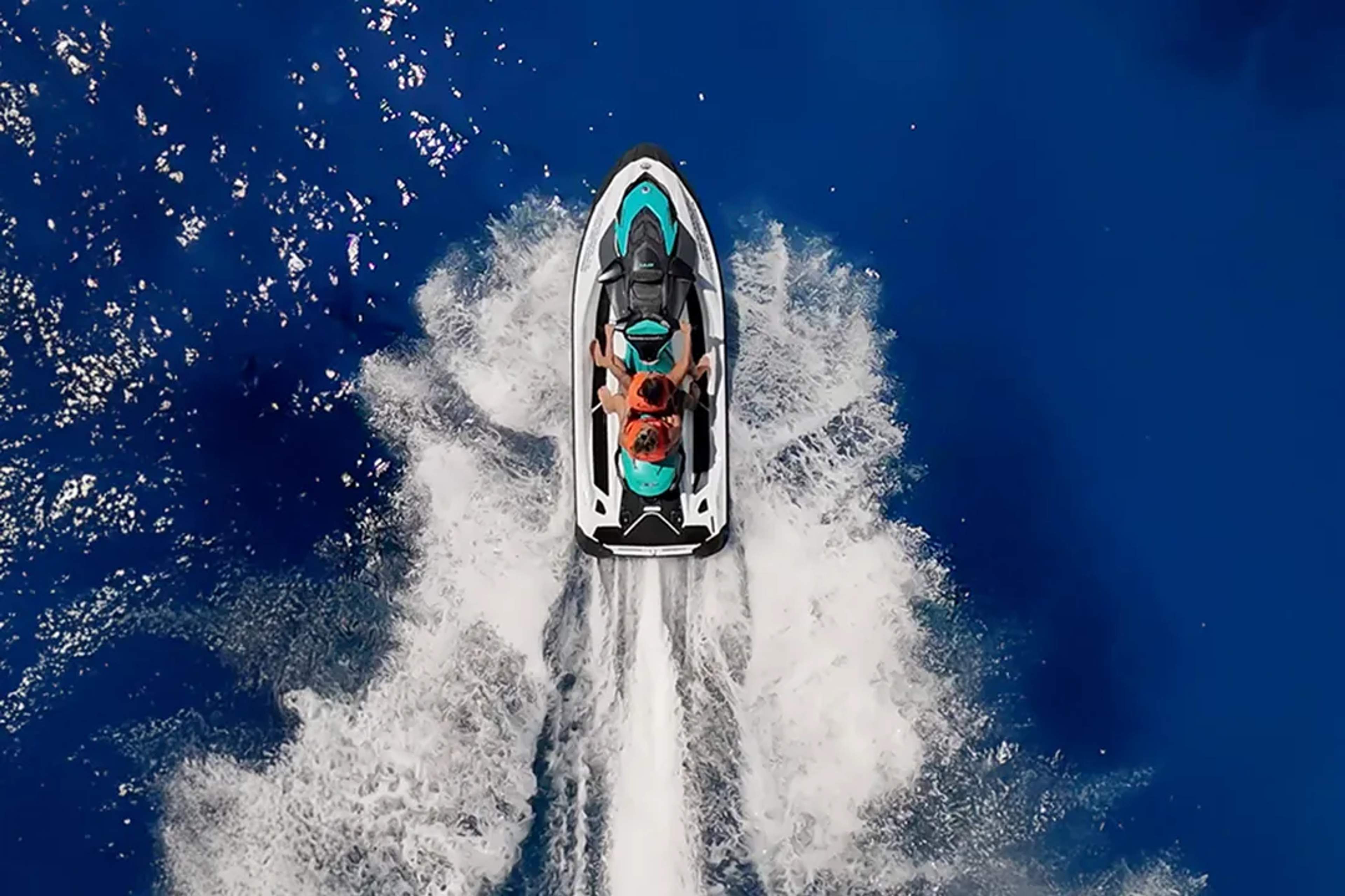 Aerial jet ski ride over deep blue ocean, couple enjoying high speed water adventure on guided tour