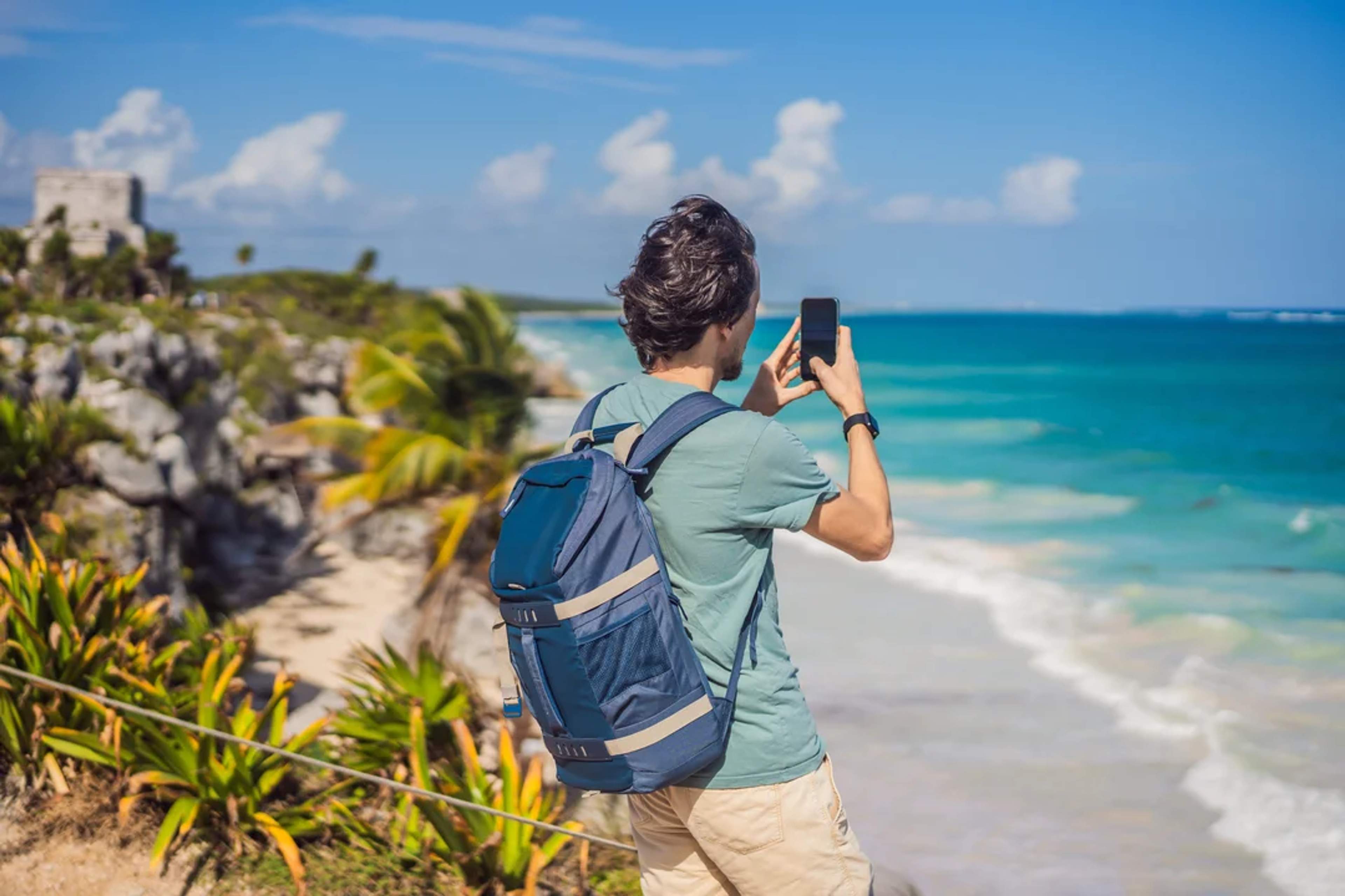 Tourist captures the view of Tulum’s coast and ruins with his phone on a sunny day.