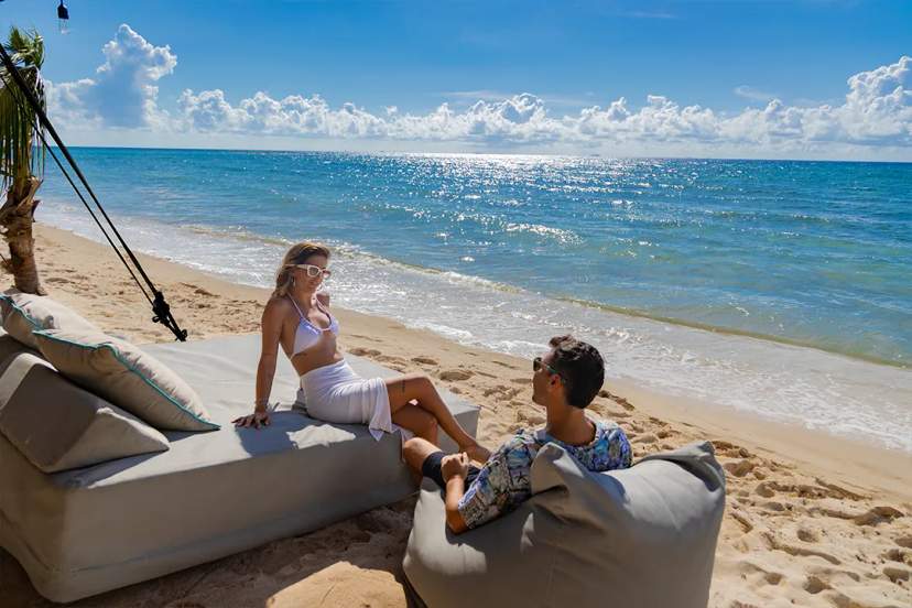 Couple relaxing on a private beach lounge during a luxury Riviera Maya beach club experience