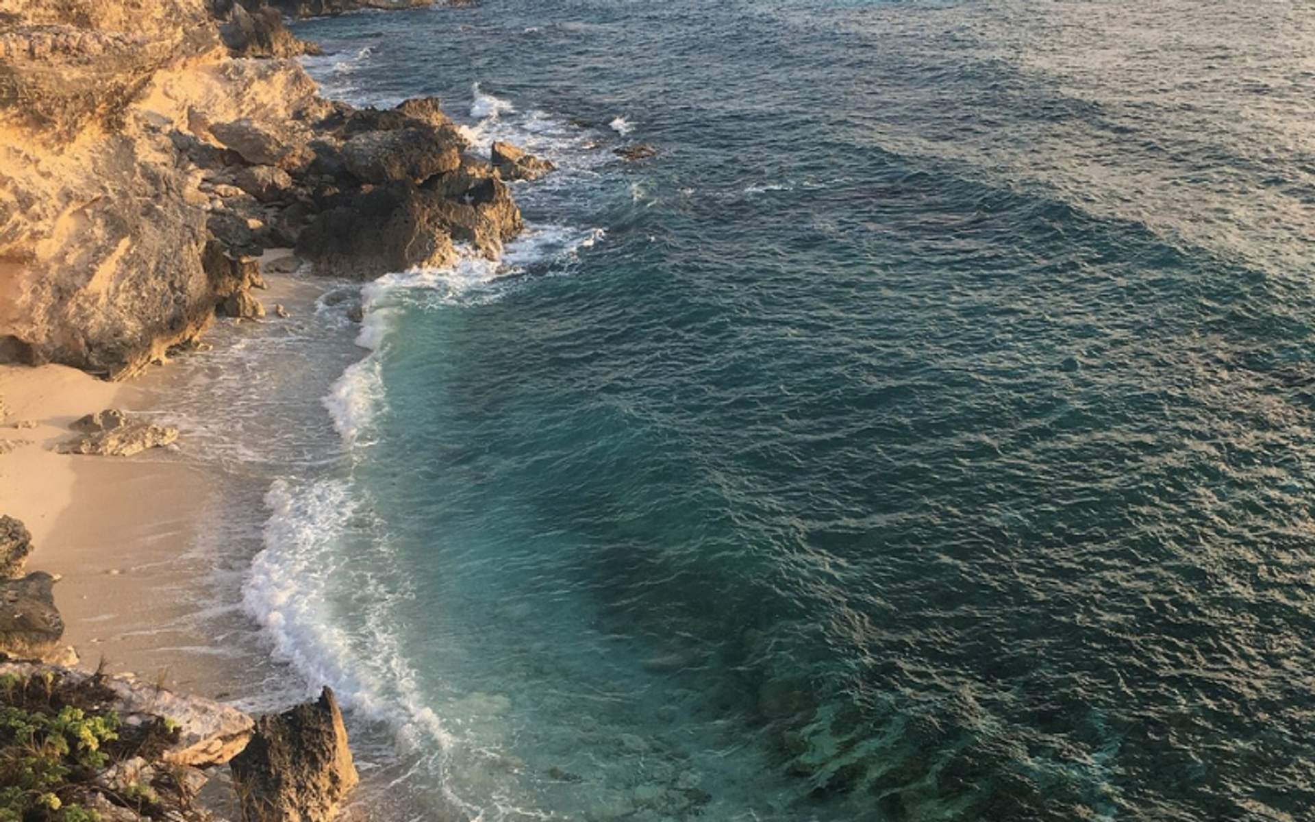 Rocky shoreline and clear turquoise waters of Isla Mujeres, offering a scenic view of the beach and ocean.