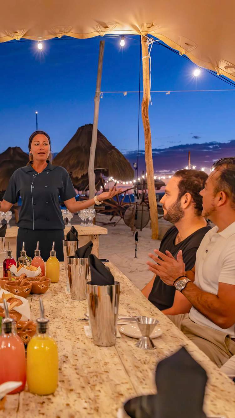 A beachfront dining experience at sunset, featuring a chef-led tasting event under a cozy canopy.