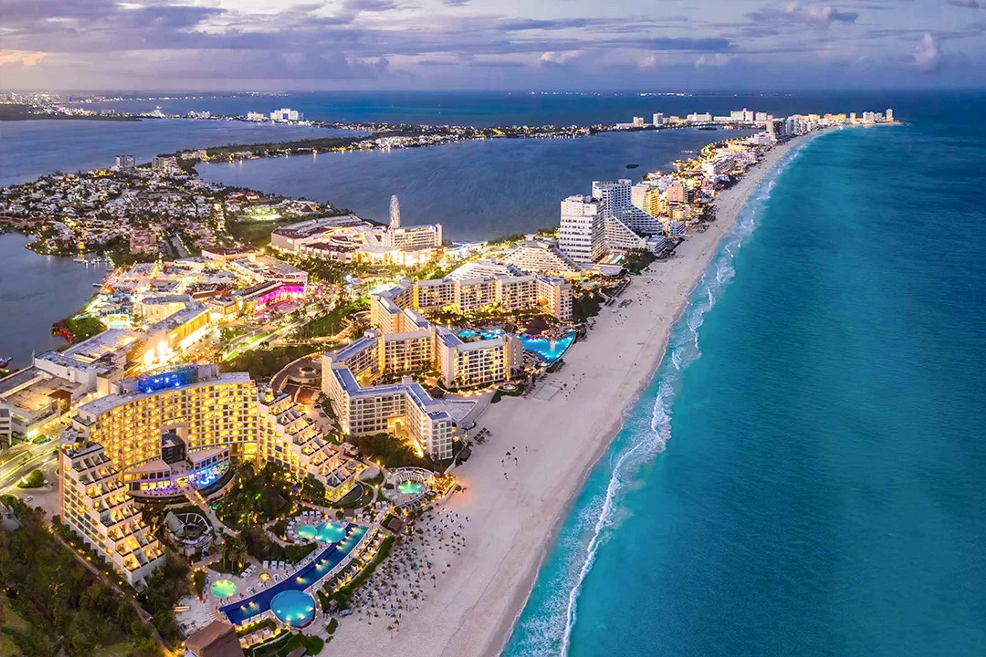 Vista aérea de la Zona Hotelera de Cancún al atardecer con el Caribe turquesa, resorts y su icónica franja costera