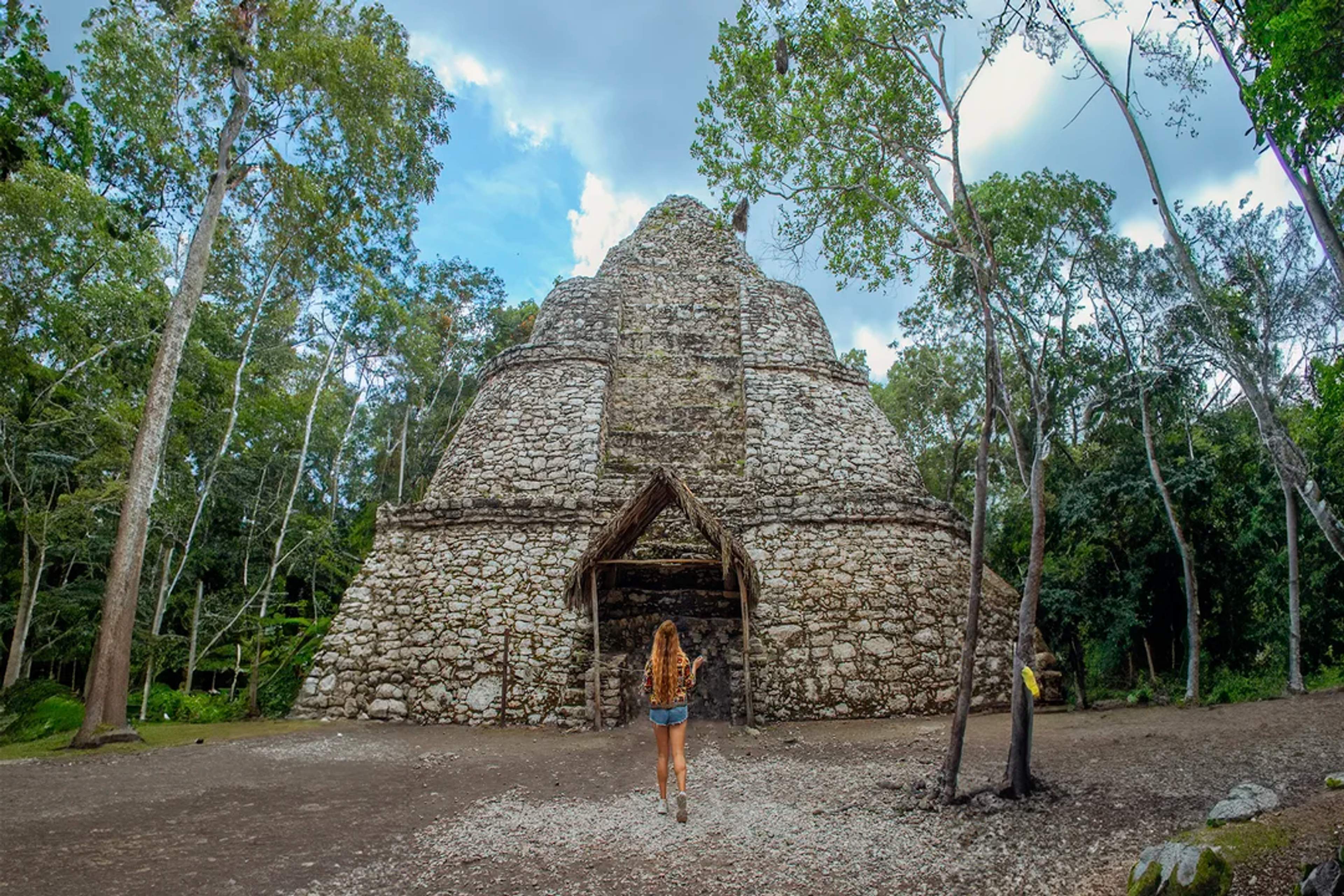 Una viajera explora una antigua pirámide maya en Cobá, rodeada de selva exuberante y un aire místico.