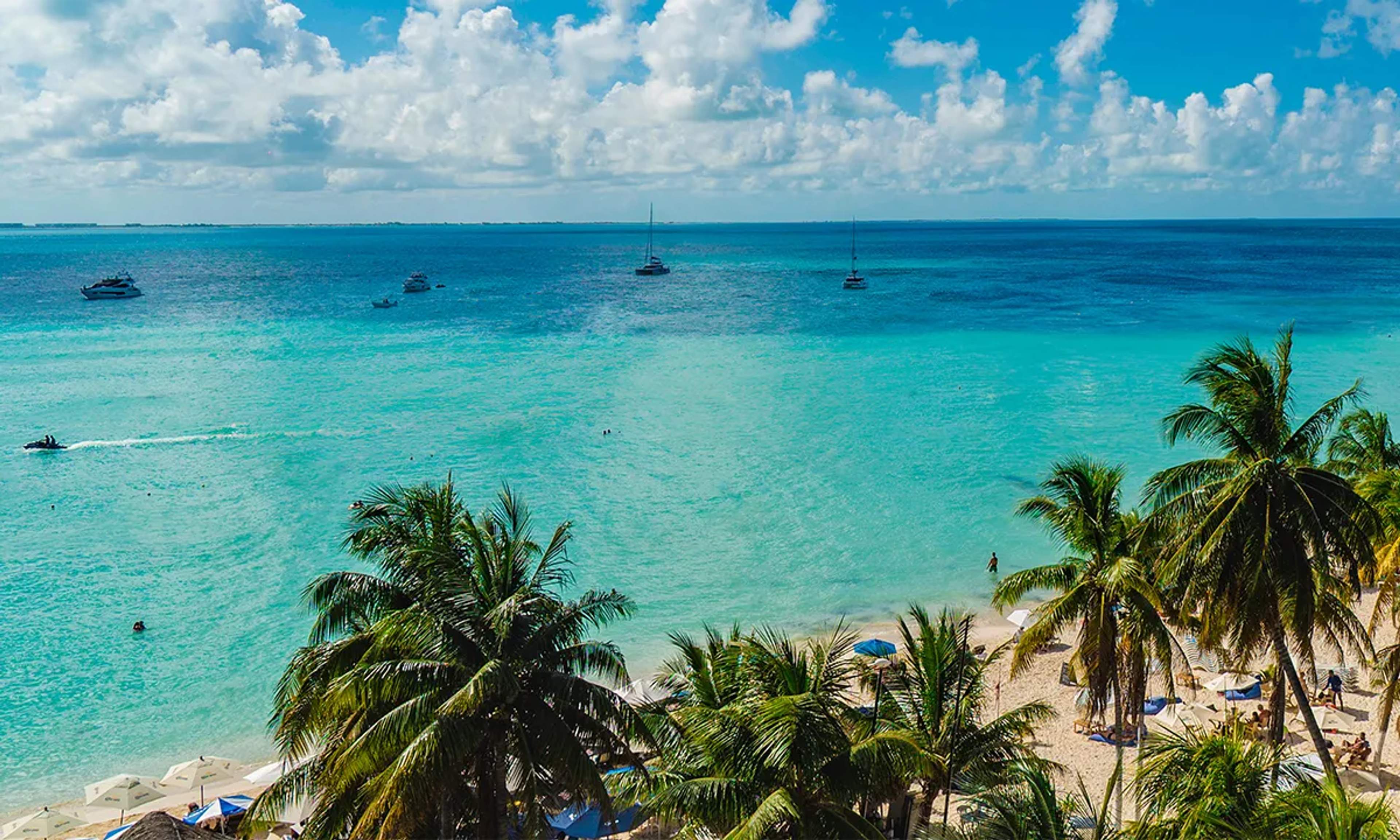 Isla Mujeres' North Beach features turquoise waters, white sands, palm trees, and a vibrant Caribbean vibe with calm seas.