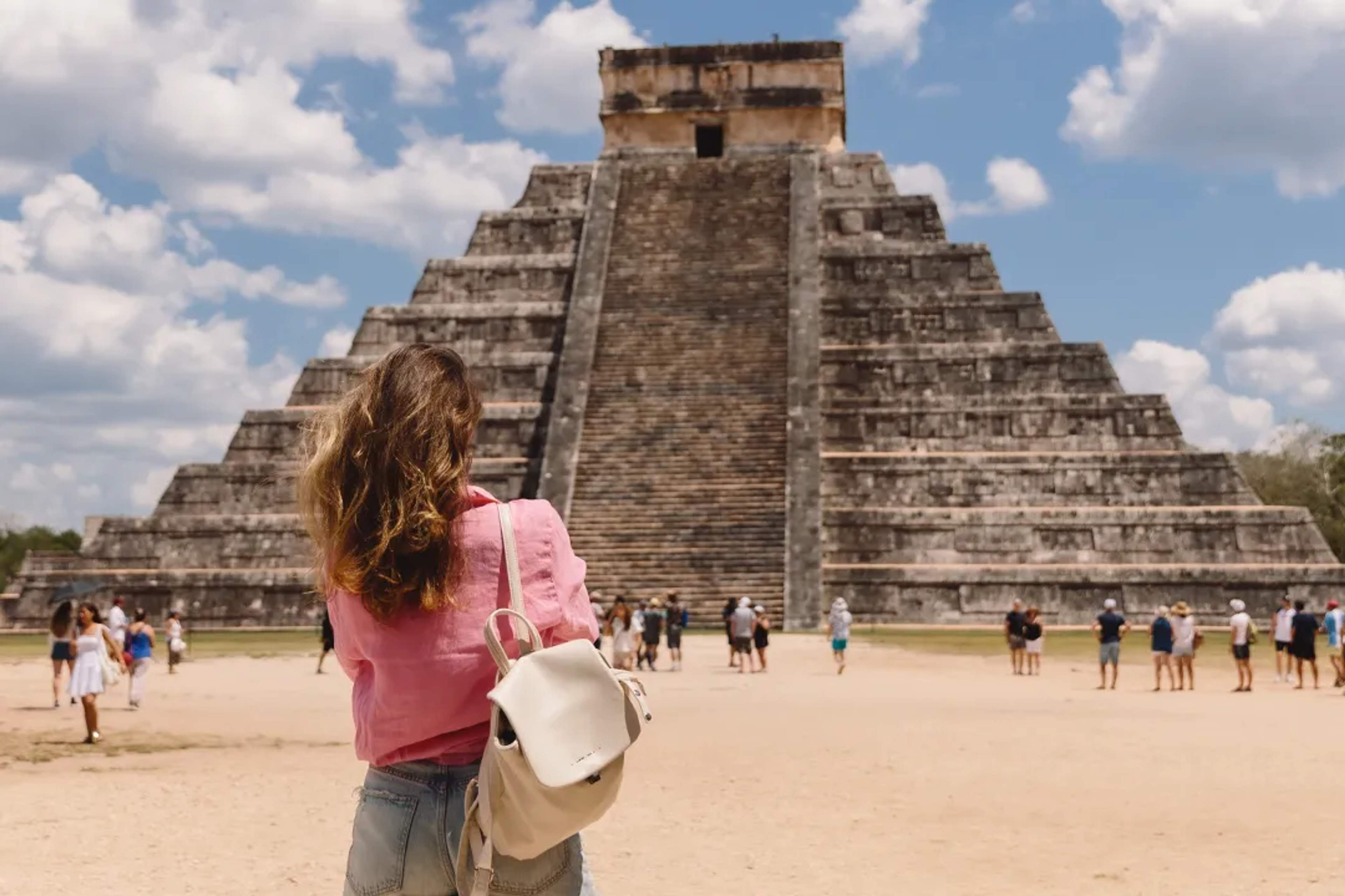 Traveler facing the Kukulkan pyramid at Chichen Itza, an iconic symbol of ancient Mayan history in Mexico