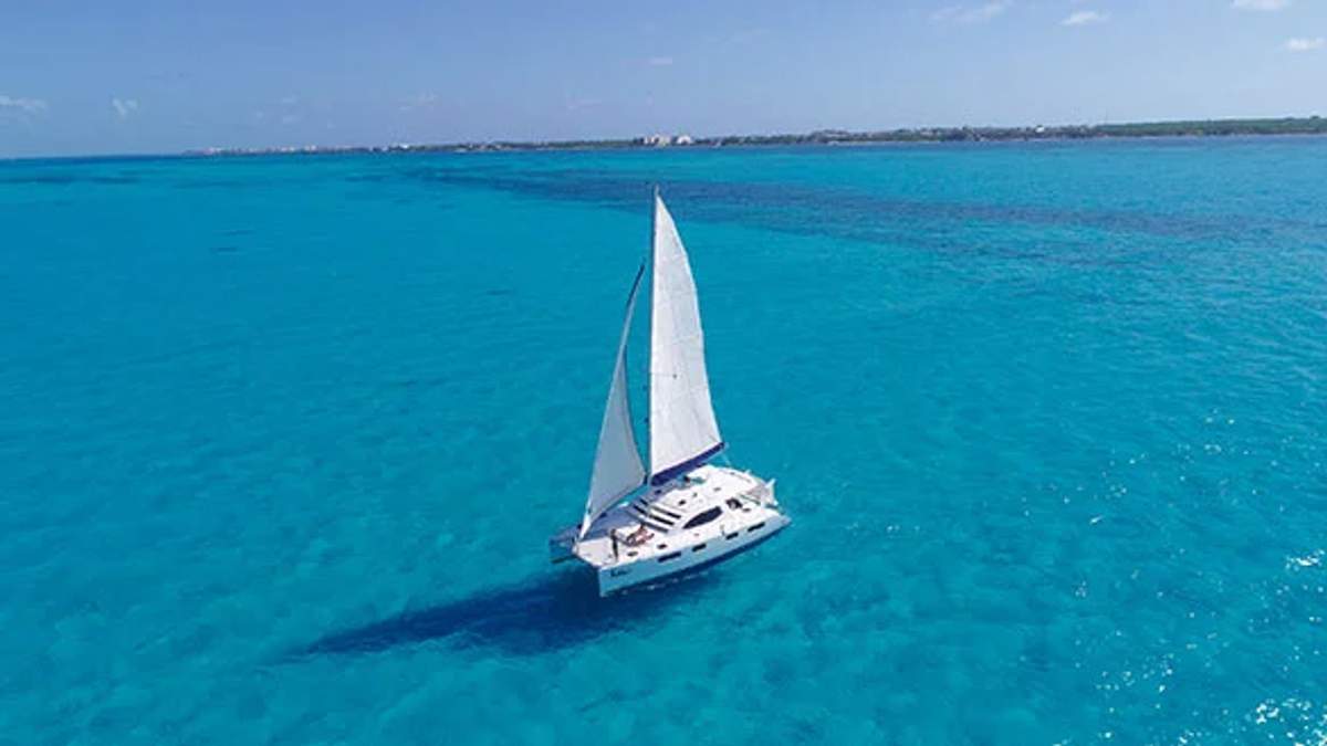 Un catamarán navegando en las claras aguas turquesas de Cancún, ofreciendo una escapada perfecta para explorar y relajarse.
