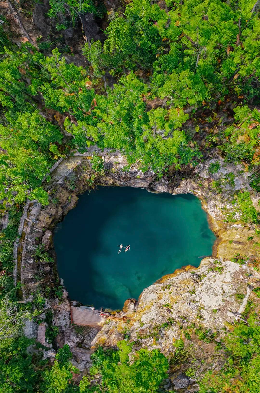 Vista aérea de dos personas nadando en un hermoso cenote