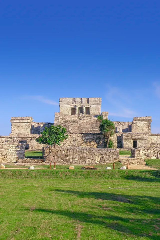 Las antiguas ruinas de Tulum se alzan frente al mar Caribe, bajo un cielo azul despejado.